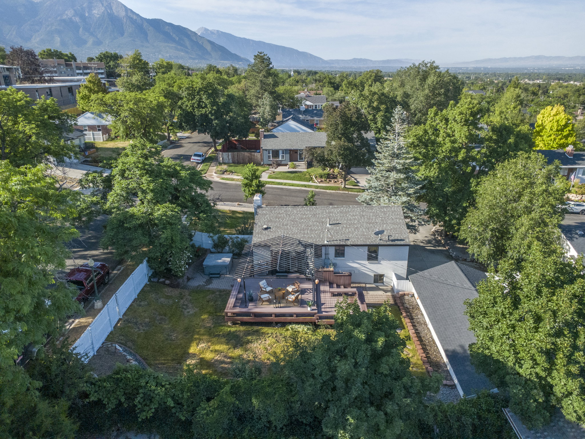 Expansive backyard featuring a multi-level wood deck, a sunken hot tub, and a white privacy fence