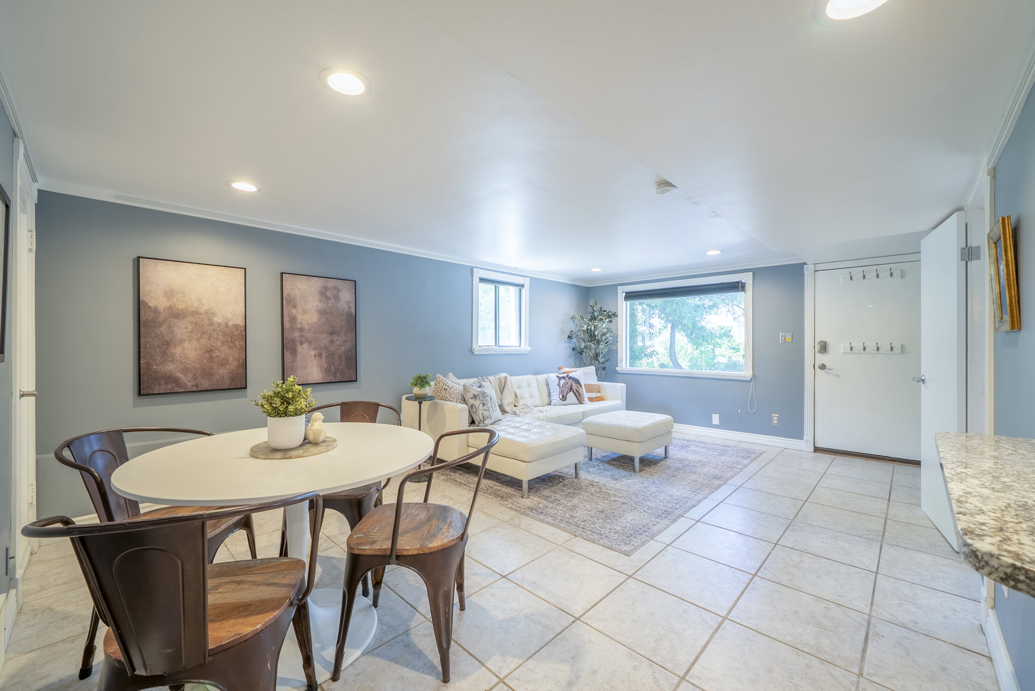 Open-concept living space featuring tiled flooring, recessed lighting, crown molding, and multiple windows