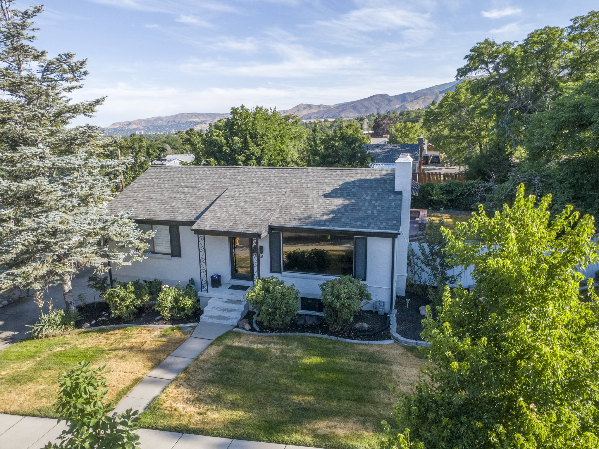 Ranch-style residence featuring a light-colored exterior with dark trim and a gabled roof