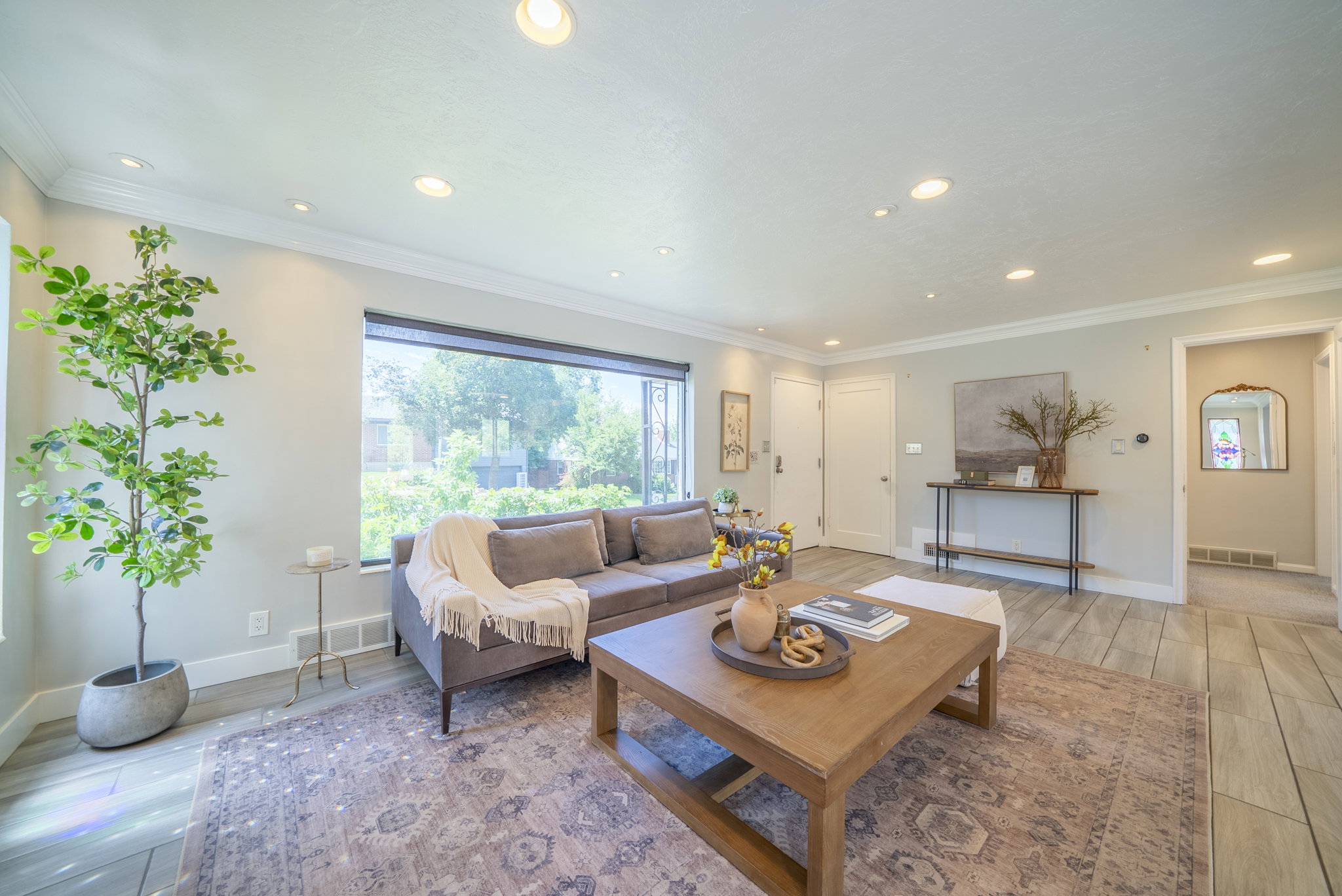 Spacious living area featuring large picture windows, recessed lighting, crown molding, wood-finish flooring, and a console table