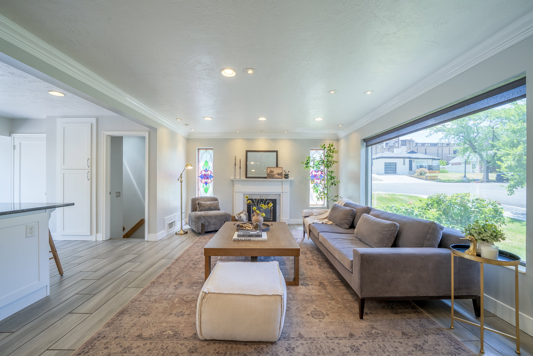 Spacious living area featuring a wide picture window, recessed lighting, and a white mantel fireplace