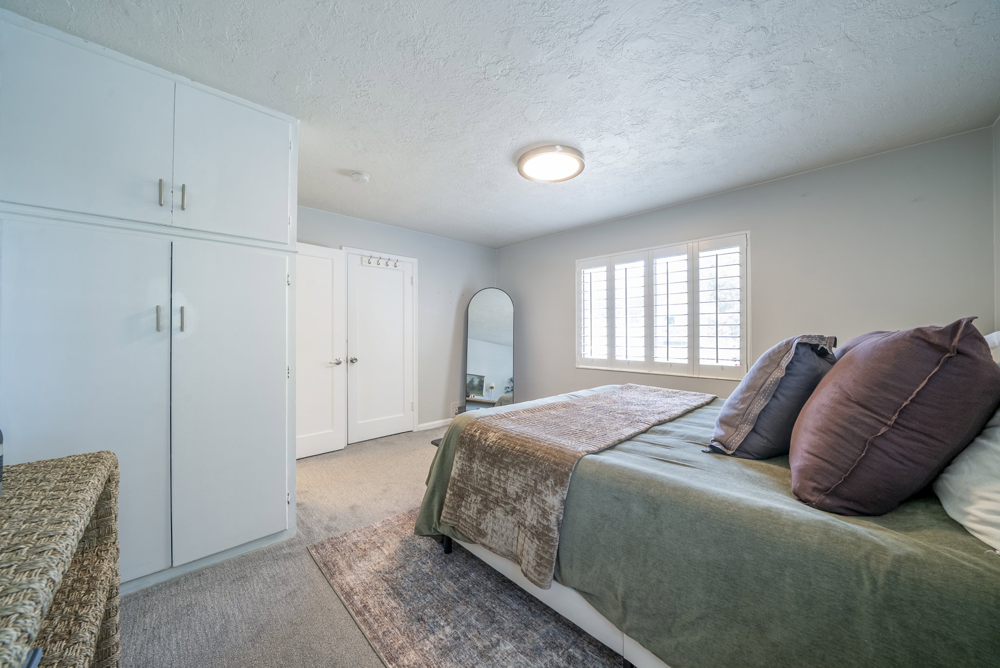 Bedroom featuring built-in cabinetry, dual interior doors, plantation shutters, and a flush-mount ceiling light