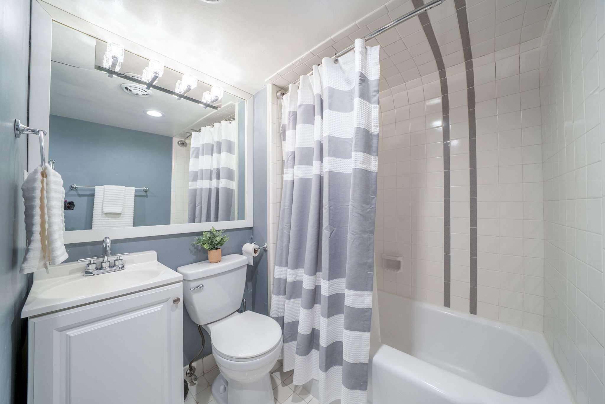 Bathroom featuring a shower-tub combination with tile surround and decorative accent strips
