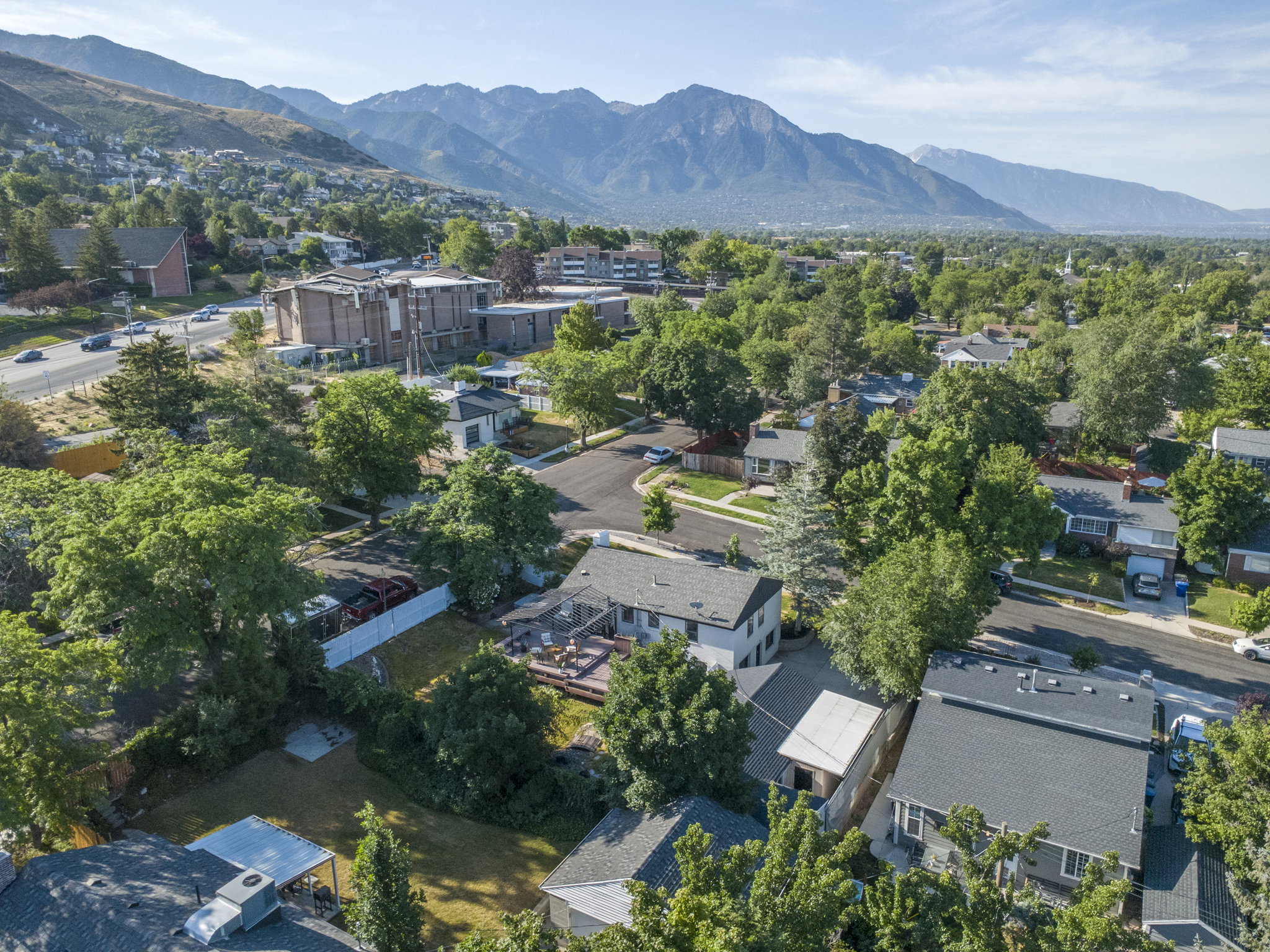 Aerial perspective highlighting a residential neighborhood with mature trees and a distant mountain range
