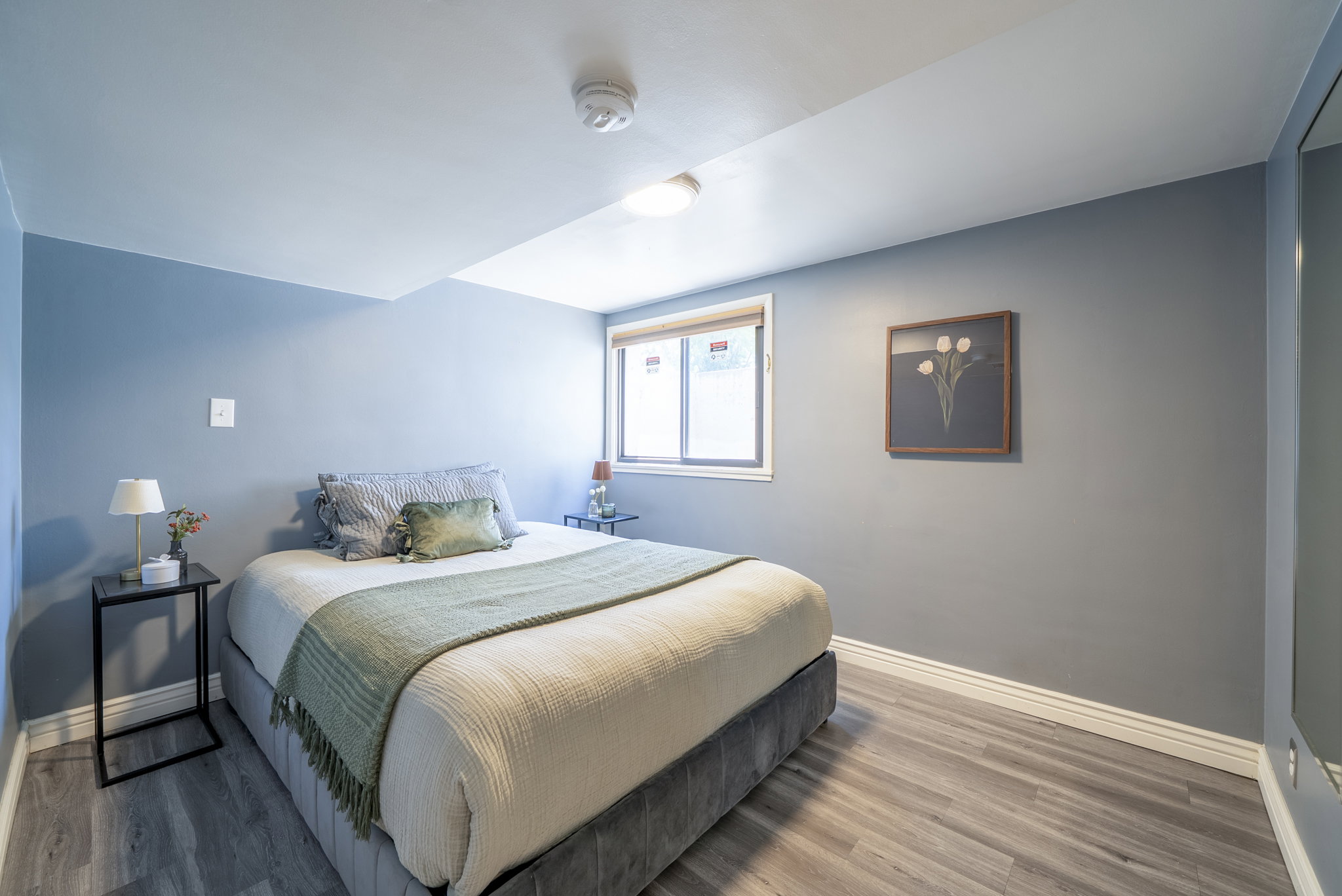 Bedroom featuring light wood-finish flooring, a window with white trim, and a built-in overhead light fixture