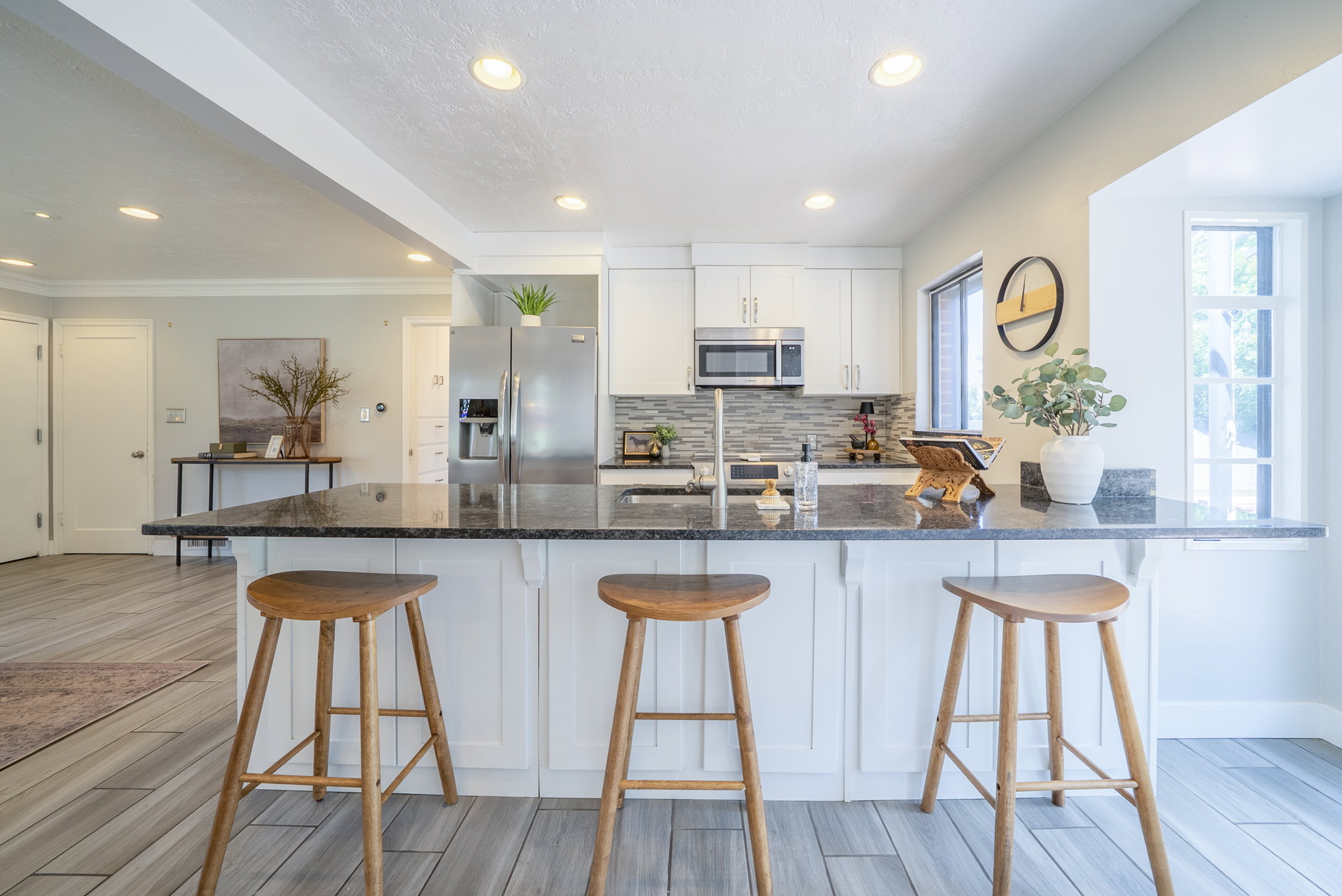 Kitchen featuring a breakfast bar with stone countertop, white cabinetry, stainless steel appliances, and wood-finish flooring