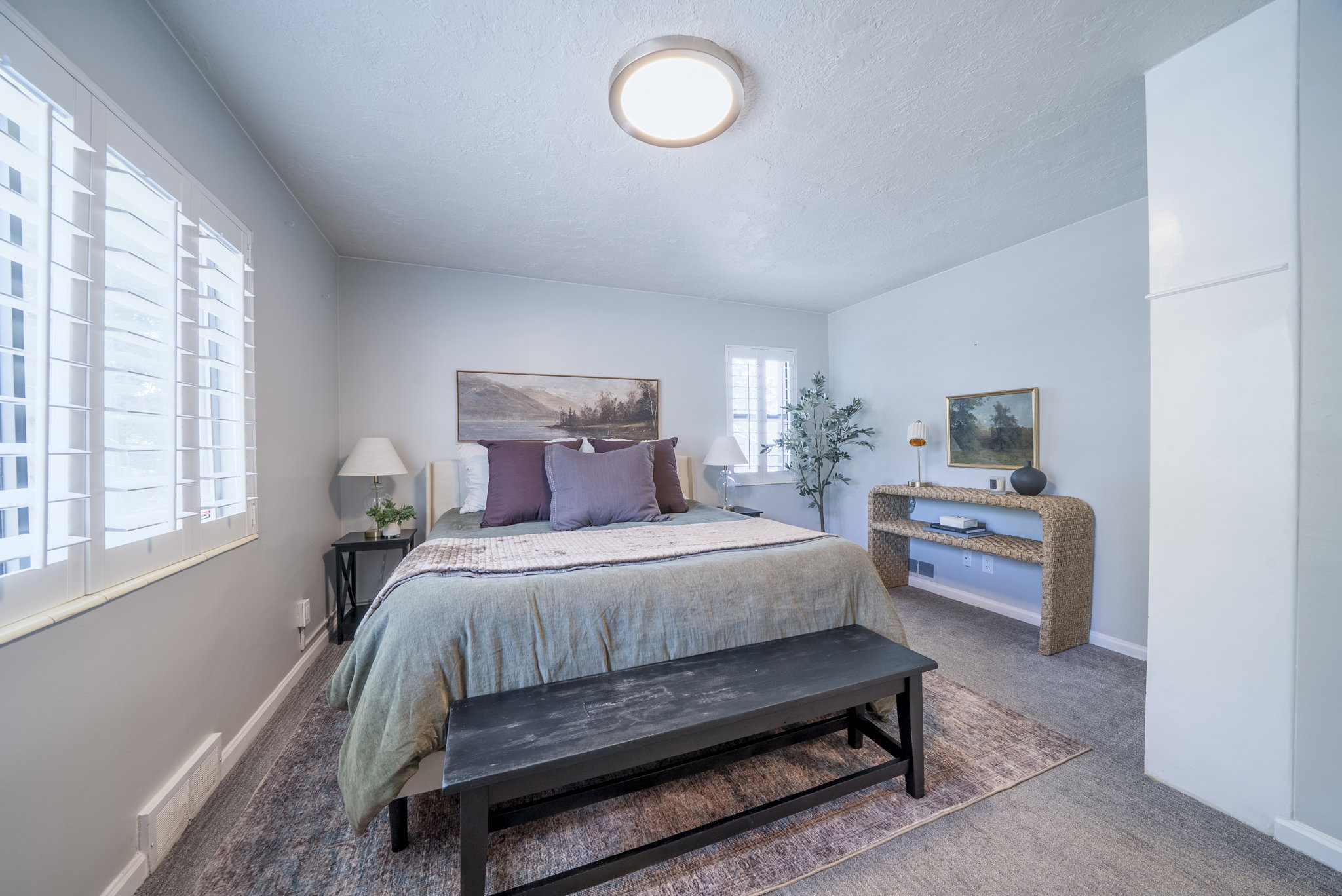 Bedroom featuring white plantation shutters, neutral tone walls, and recessed lighting