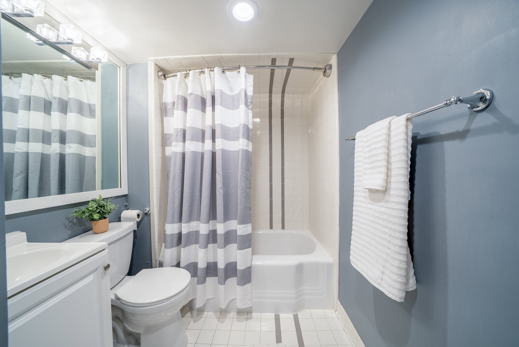 Bathroom featuring a white vanity with integrated sink, toilet, and a bathtub with tiled surround