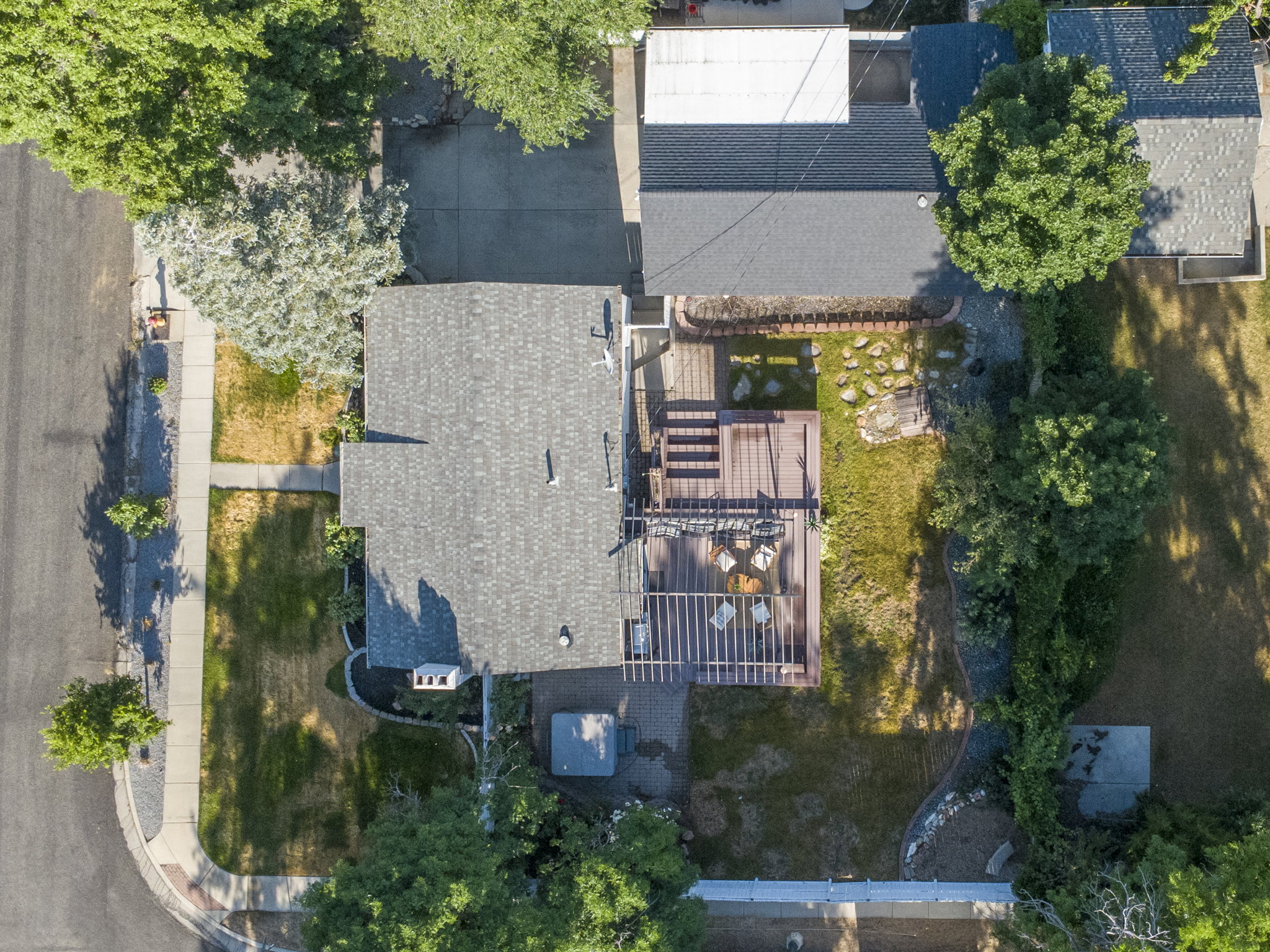 Expansive backyard featuring a multi-level wood deck, a pergola, a stone patio area, and mature perimeter trees