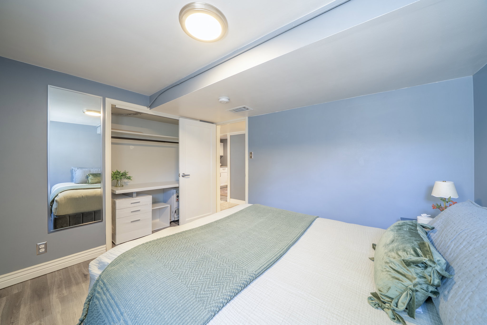 Bedroom featuring wood-finish flooring, a flush-mount ceiling light, and light blue wall tones