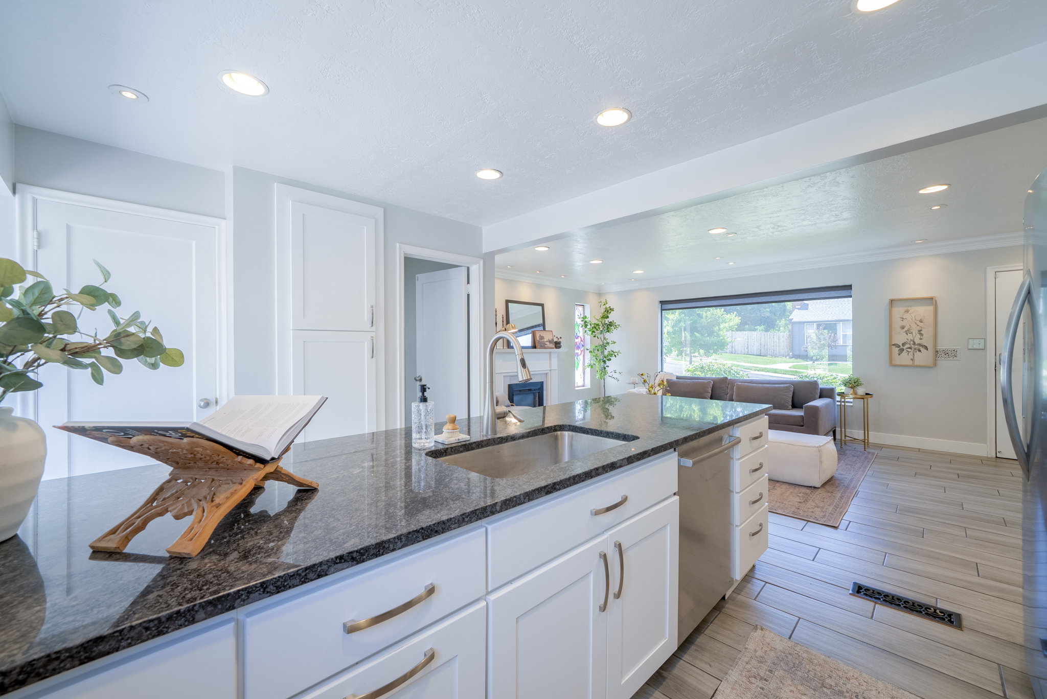 Kitchen island featuring a dark granite countertop, undermount sink, and stainless steel dishwasher