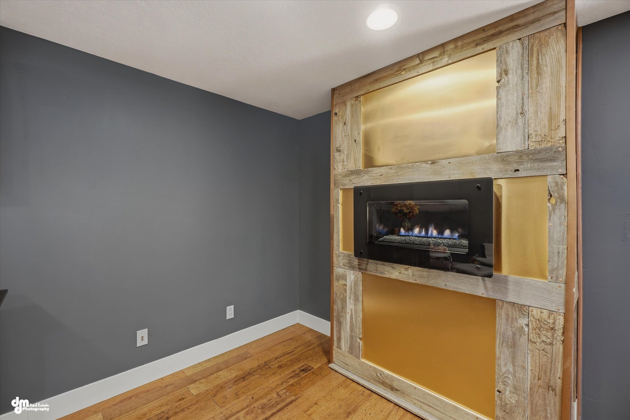 Accent wall featuring a built-in linear fireplace with a metal frame, wood-finish flooring, and recessed ceiling lighting