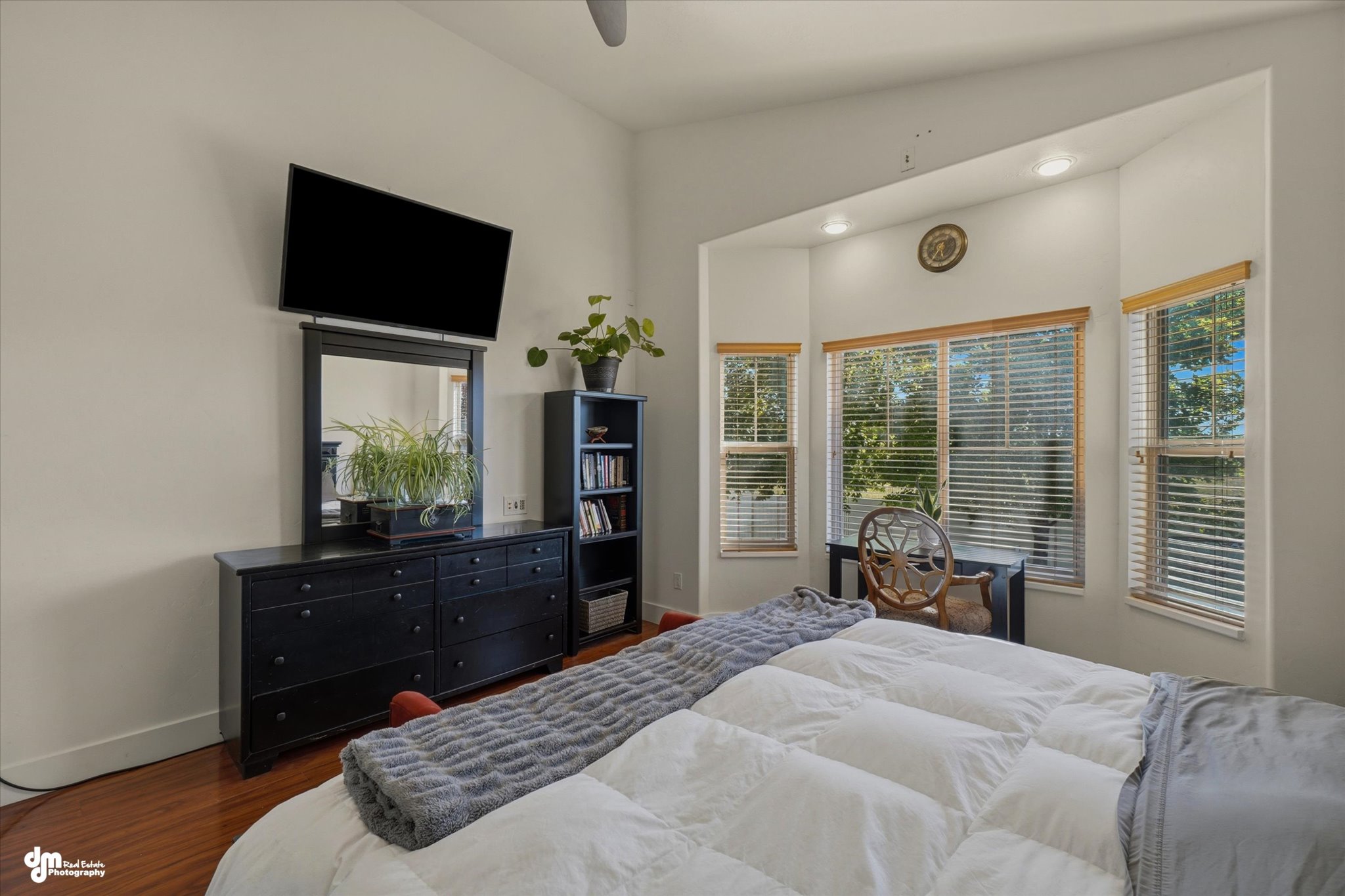 Spacious room featuring a bay window with natural wood trim, recessed lighting, wood-finish flooring, and a vaulted ceiling