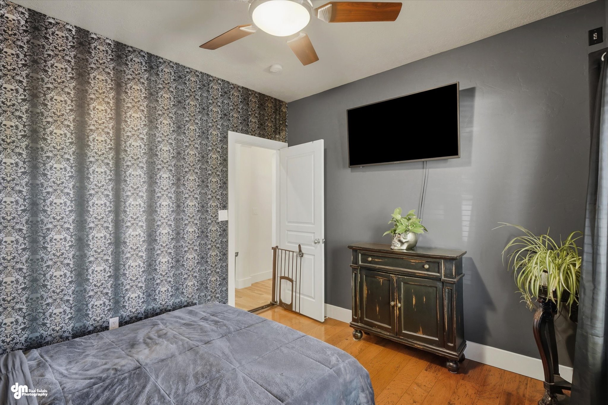 Bedroom featuring patterned wallpaper, wood-finish flooring, and a ceiling fan with integrated lighting