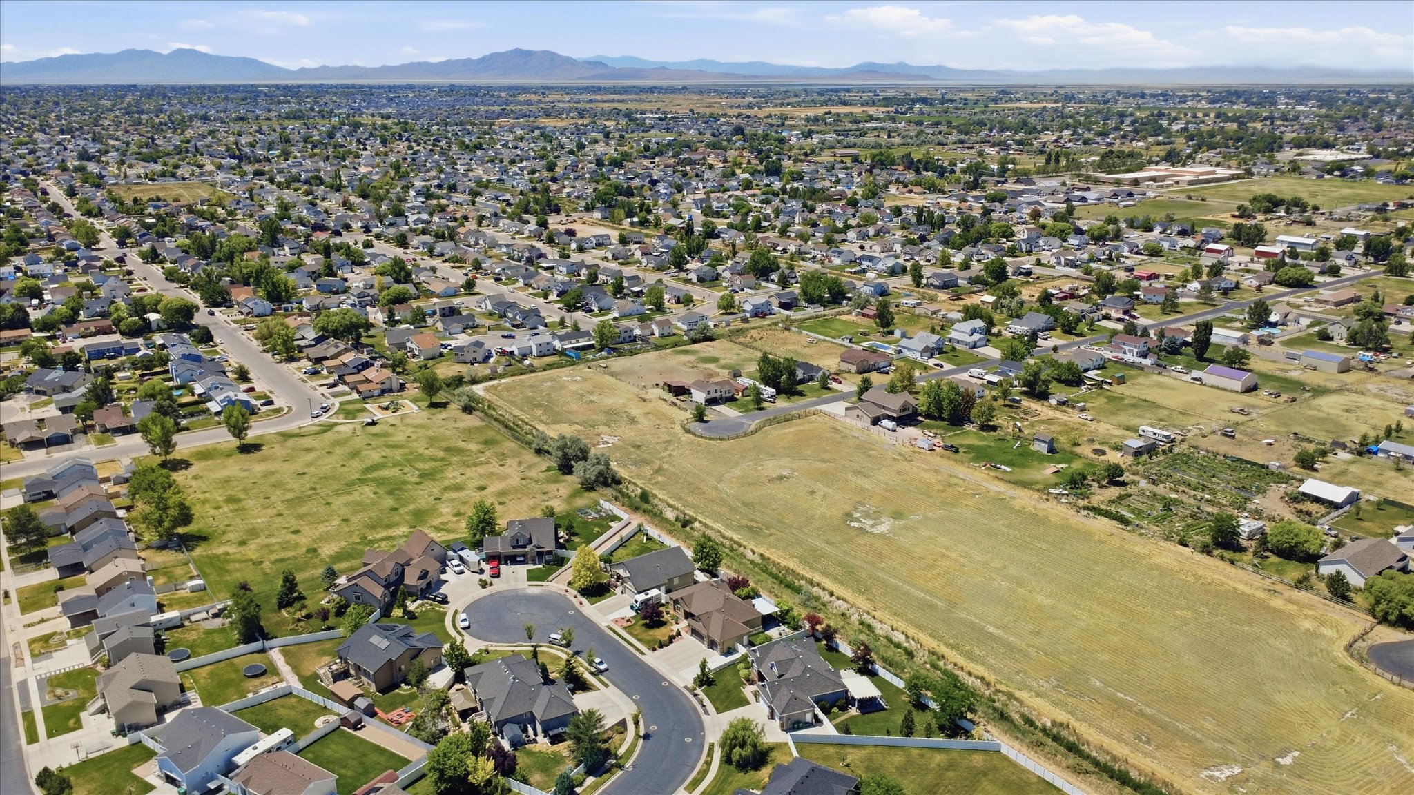Expansive aerial perspective showcasing a residential development with established homes and undeveloped land parcels