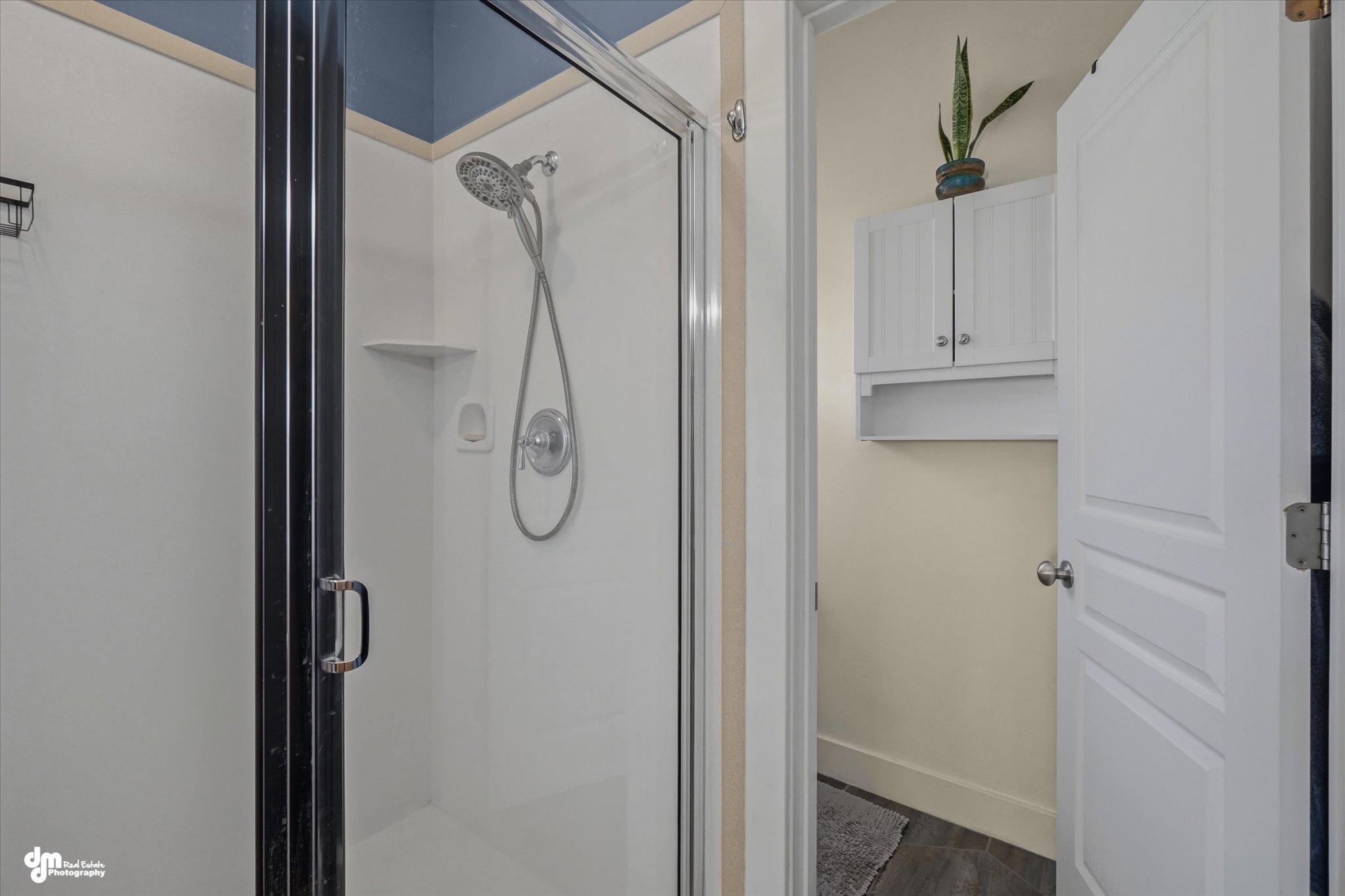 Shower enclosure with clear glass door and black framing, featuring a wall-mounted shower head and built-in shelving