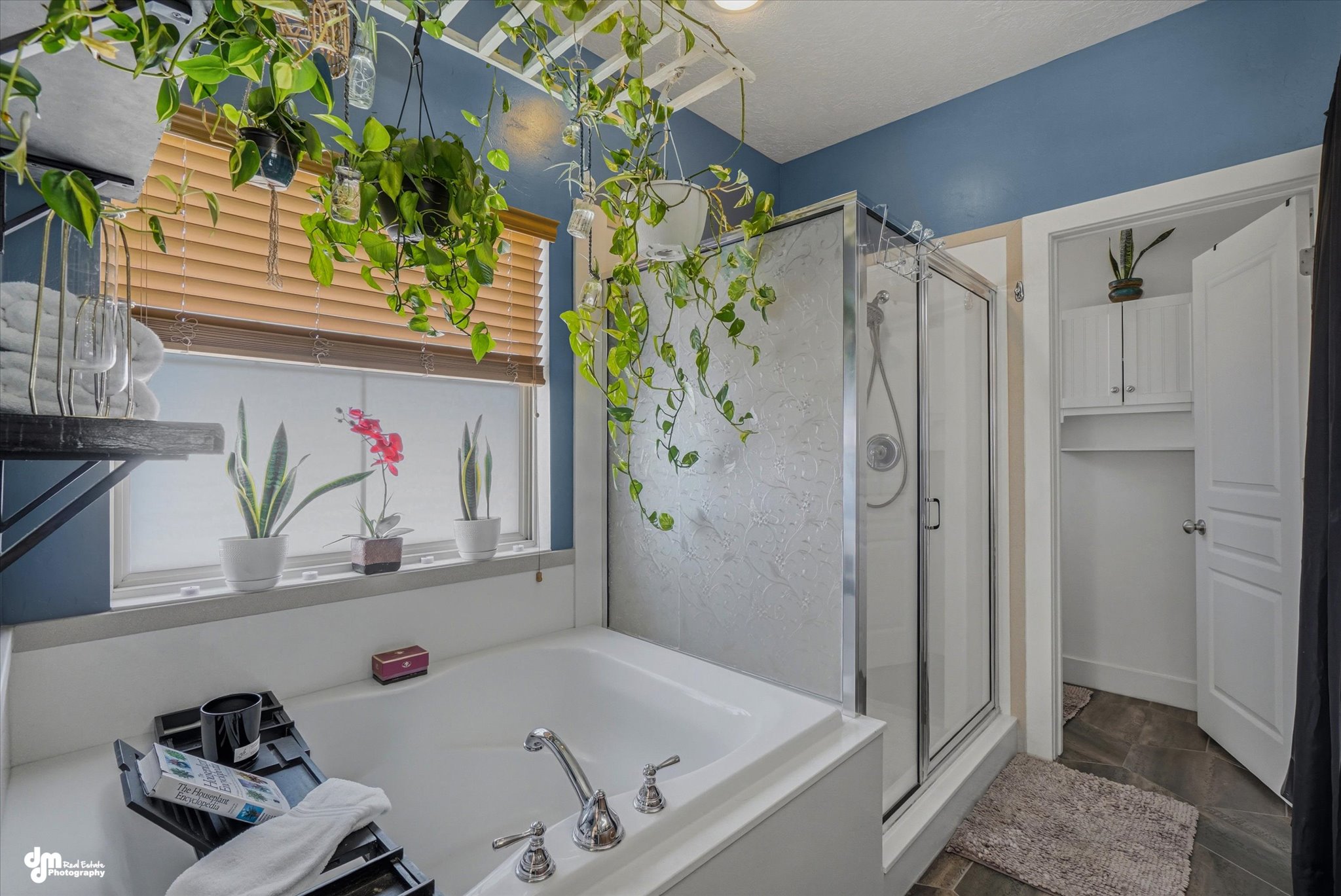 Bathroom featuring a built-in tub, a glass-enclosed shower with a brushed nickel showerhead, and window with wood-finish blinds