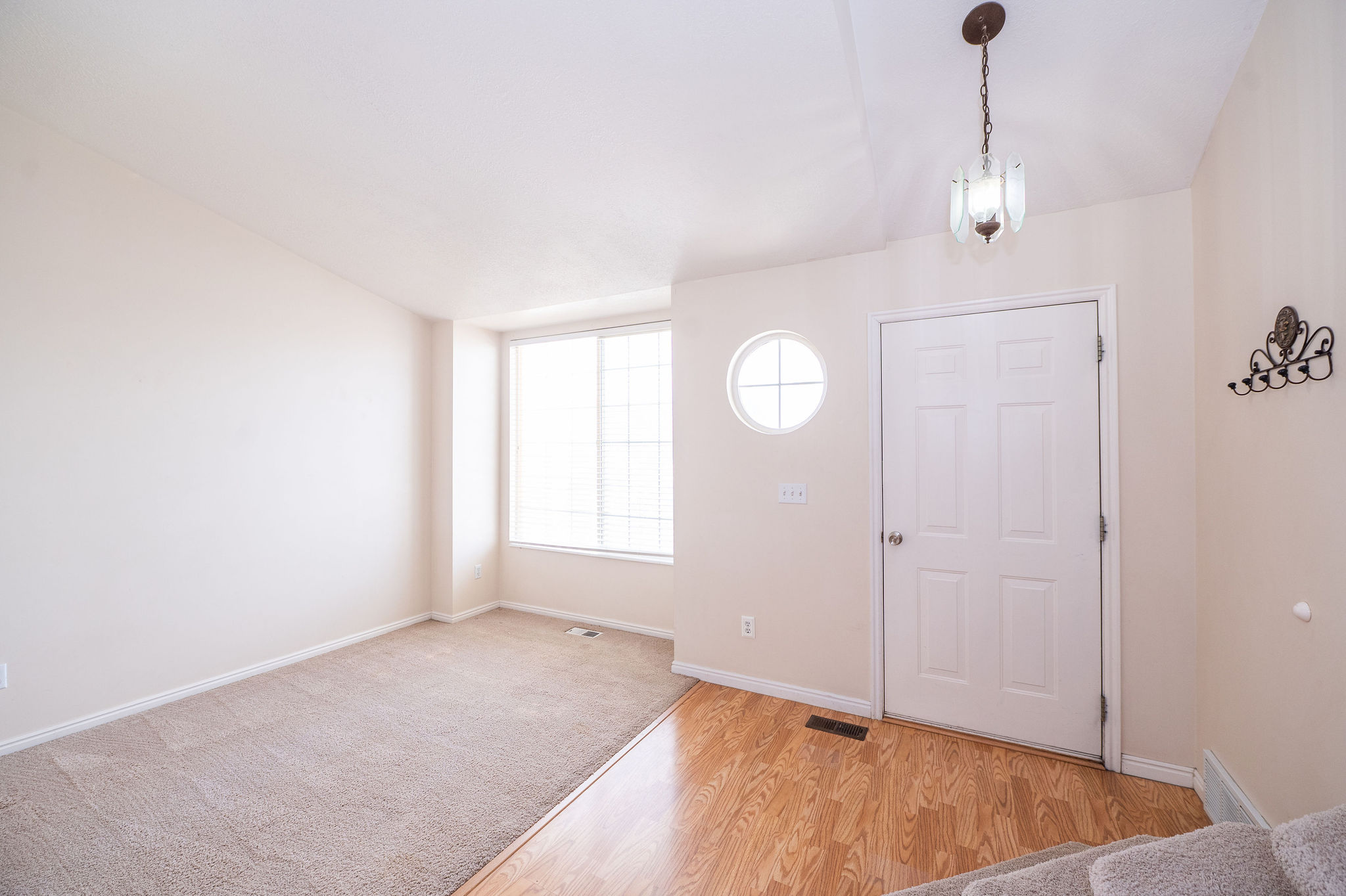 Entryway featuring wood-finish flooring, a white paneled door, and a decorative pendant light