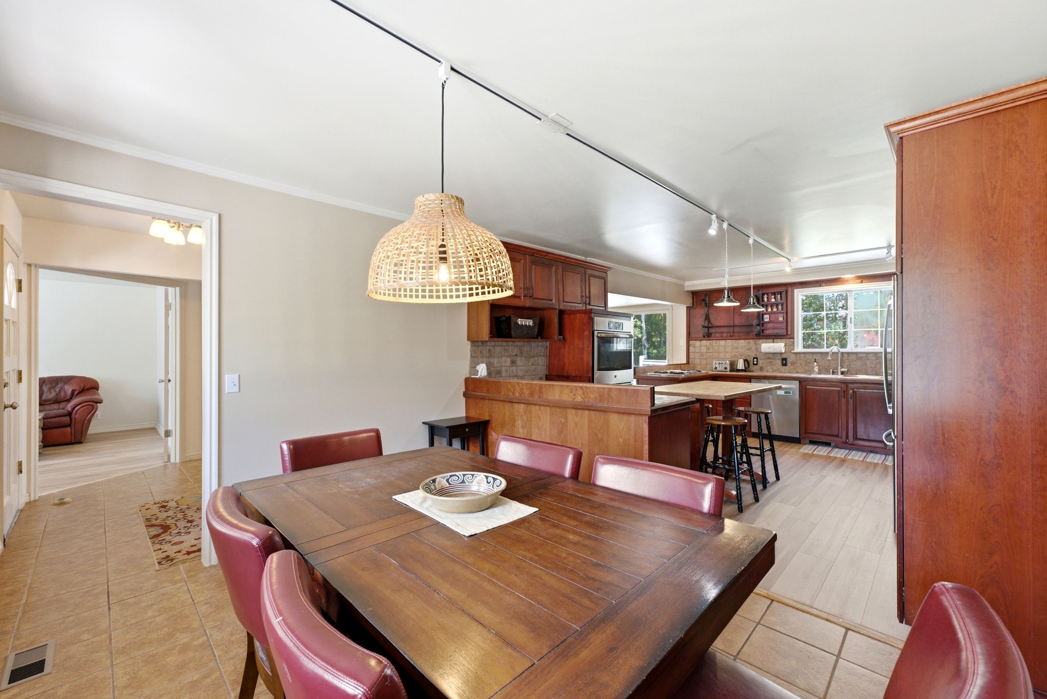Open-concept dining area with a woven pendant light, tile flooring, and a dining table
