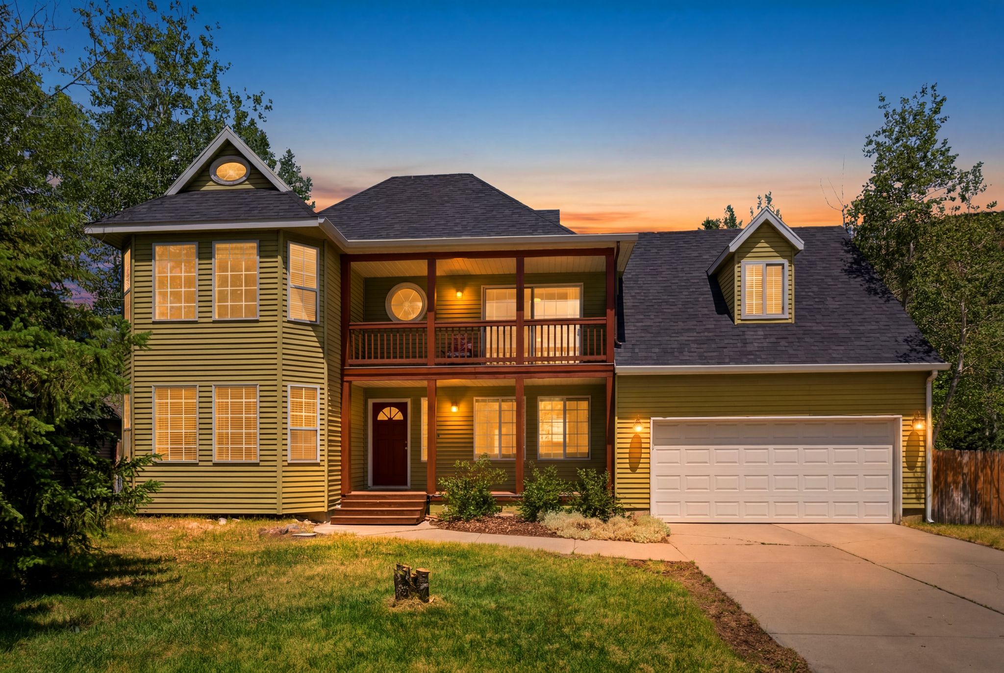 Two-story residence featuring a prominent covered balcony, a two-car garage, and multiple dormer windows