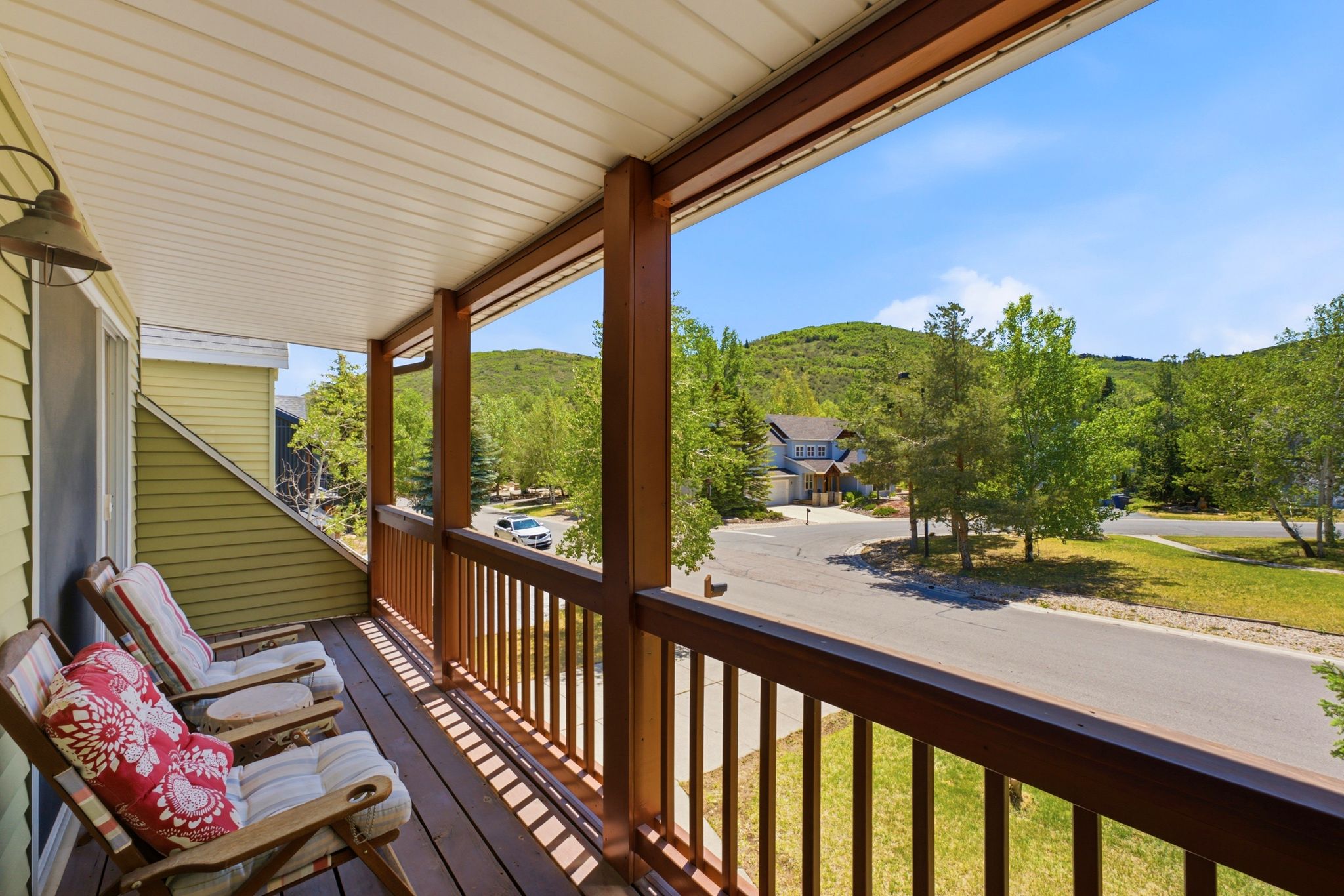 Covered outdoor deck with wood-finish flooring, sturdy wood-tone railings, and a slatted ceiling