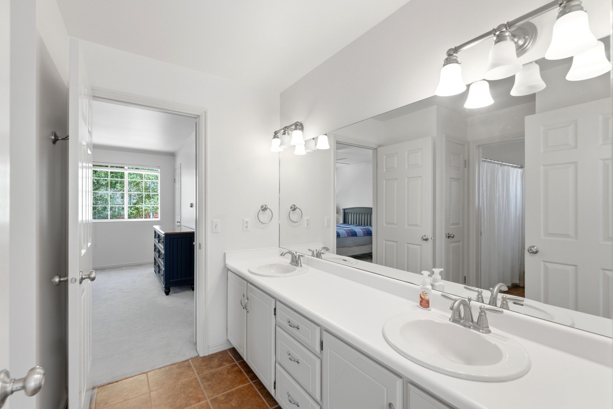 Dual vanity with integrated sinks, brushed nickel fixtures, and a full-width mirror
