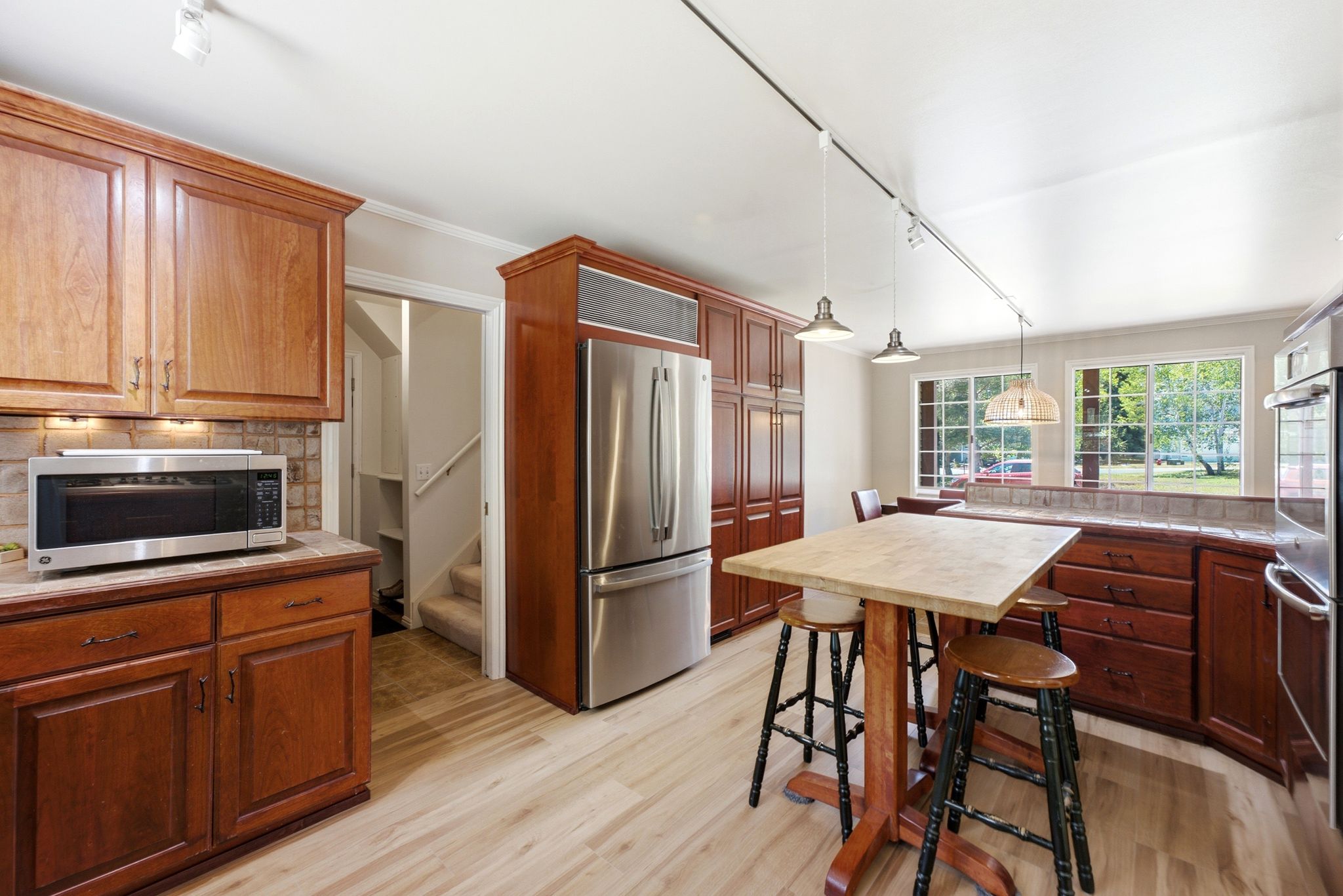 Kitchen featuring wood cabinetry, stainless steel appliances, a tile backsplash, and light wood-finish flooring