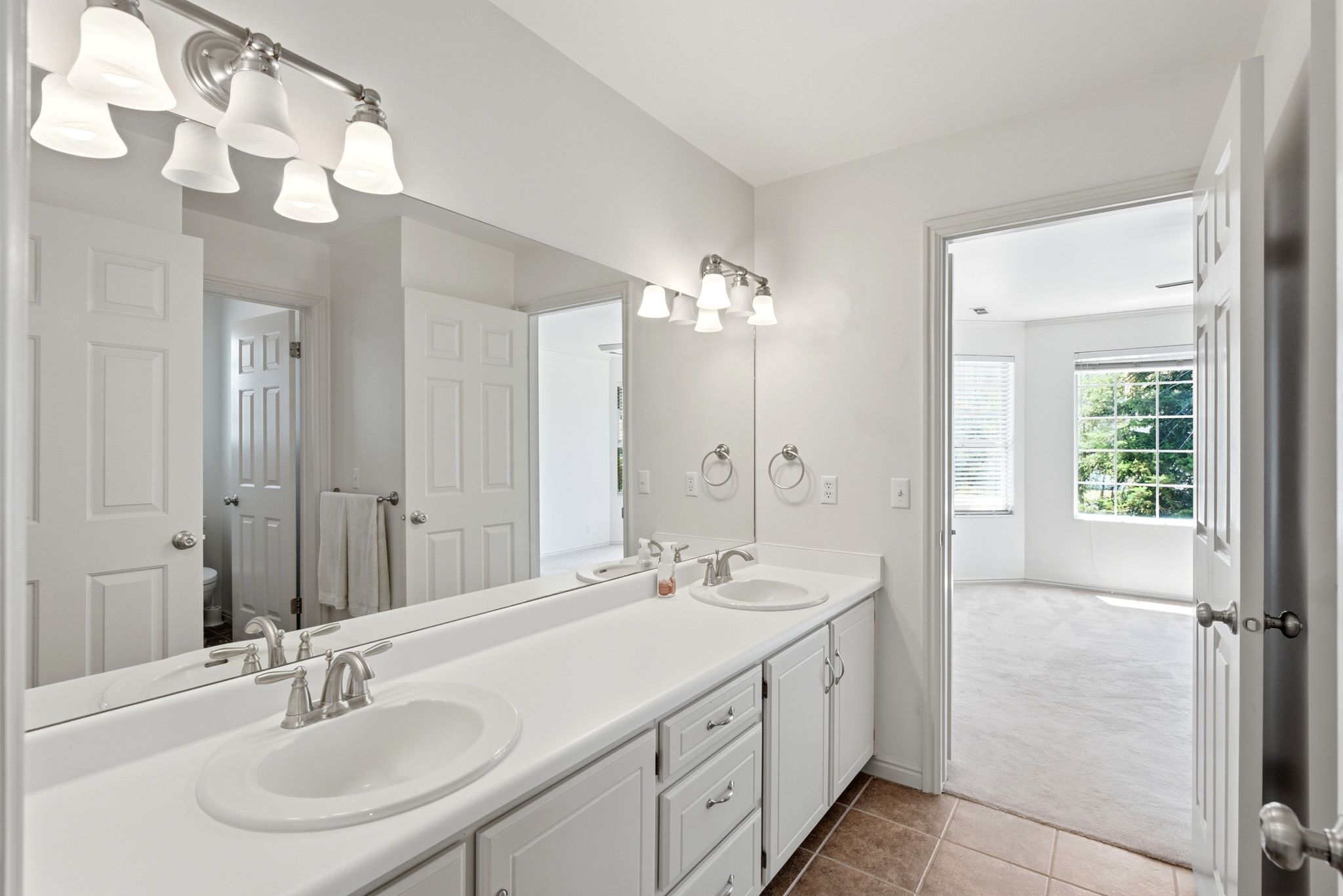 Bathroom featuring a double vanity with white cabinetry, integrated sinks, and brushed nickel faucets
