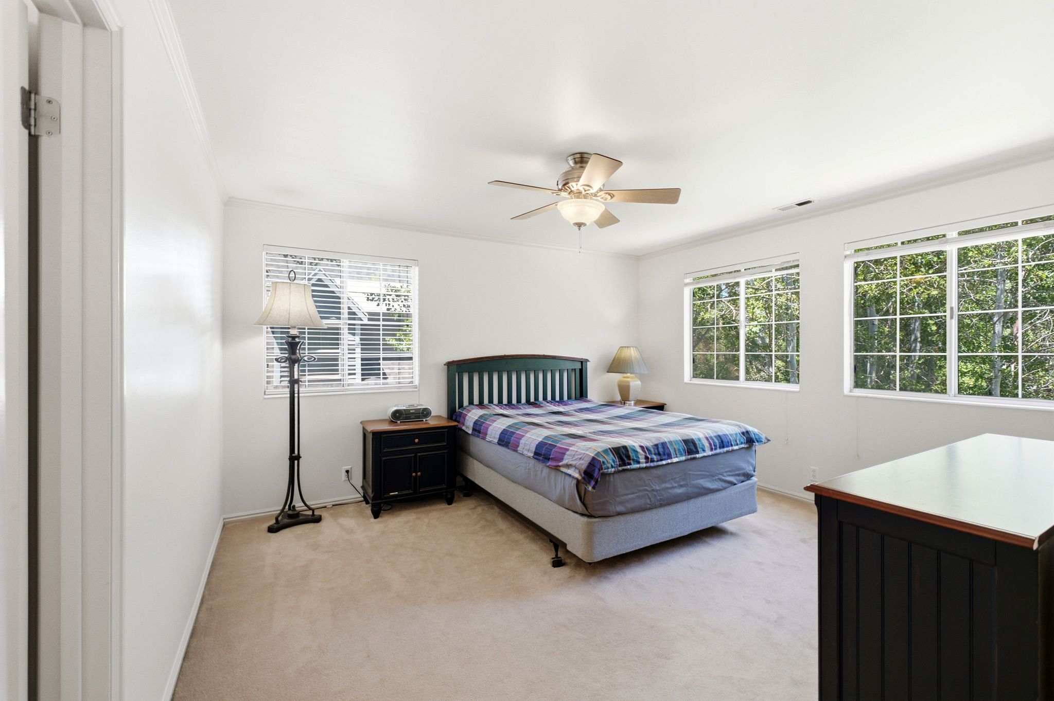 Spacious room featuring neutral carpeting, a ceiling fan with integrated lighting, and multiple windows