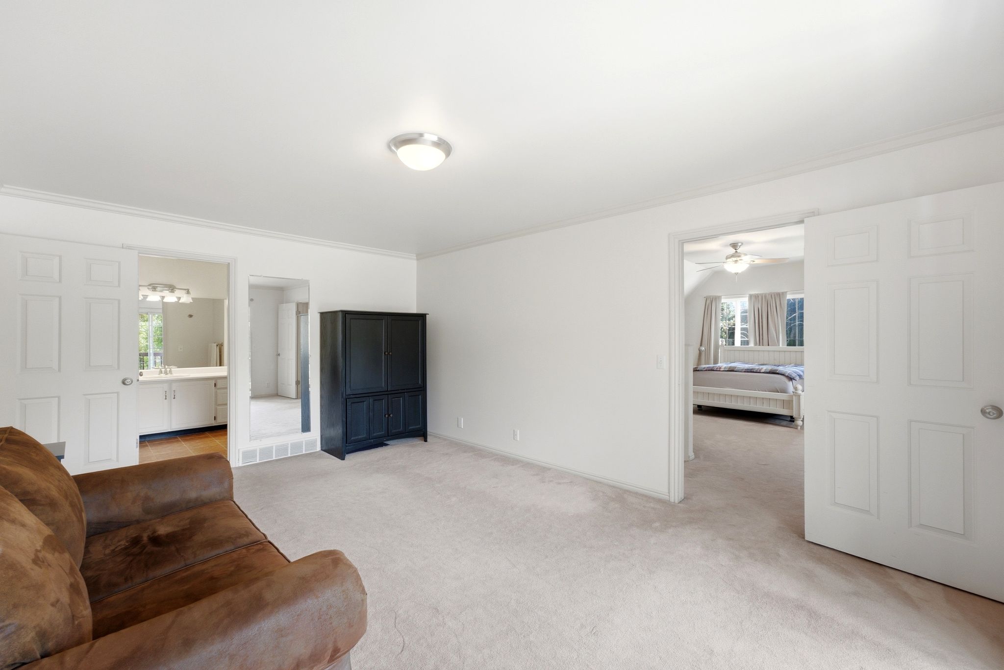 Spacious room featuring light carpeting and white walls, with a brushed nickel flush mount ceiling light