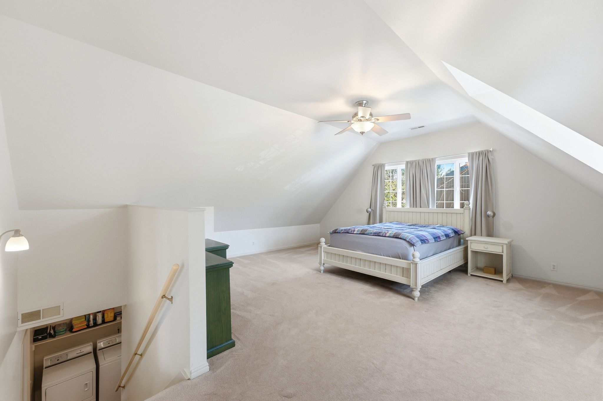 Spacious attic room with vaulted ceilings, recessed windows, a ceiling fan, and light-toned carpeting