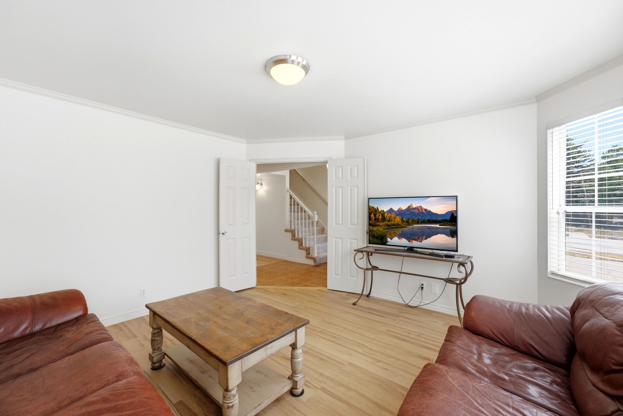 Spacious room featuring wood-finish flooring, white baseboards, and crown molding