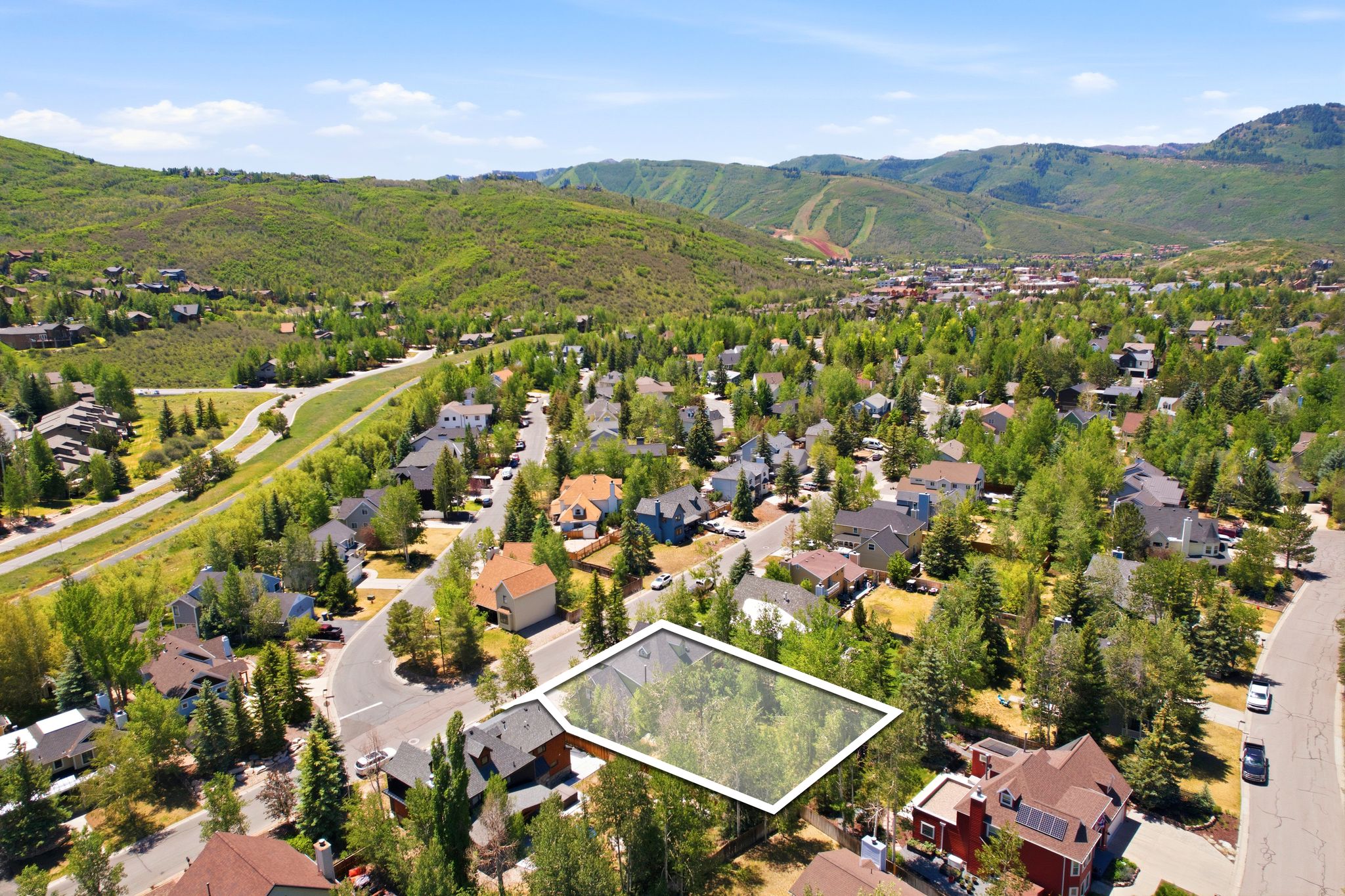 Elevated property with surrounding established residences, mature trees, and mountainous terrain