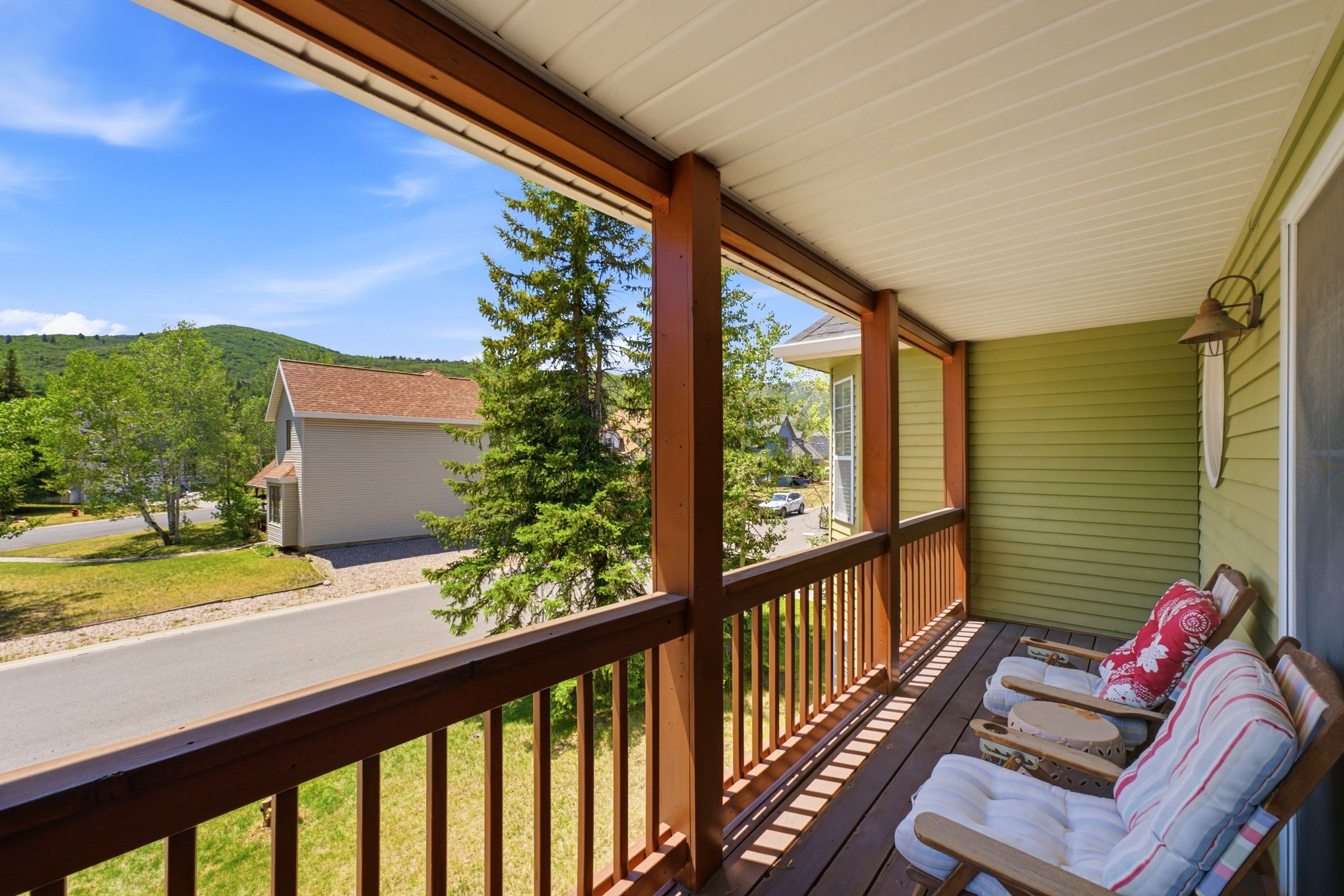 Covered porch featuring dark wood-finish flooring, sturdy wood pillars, and a matching wood railing