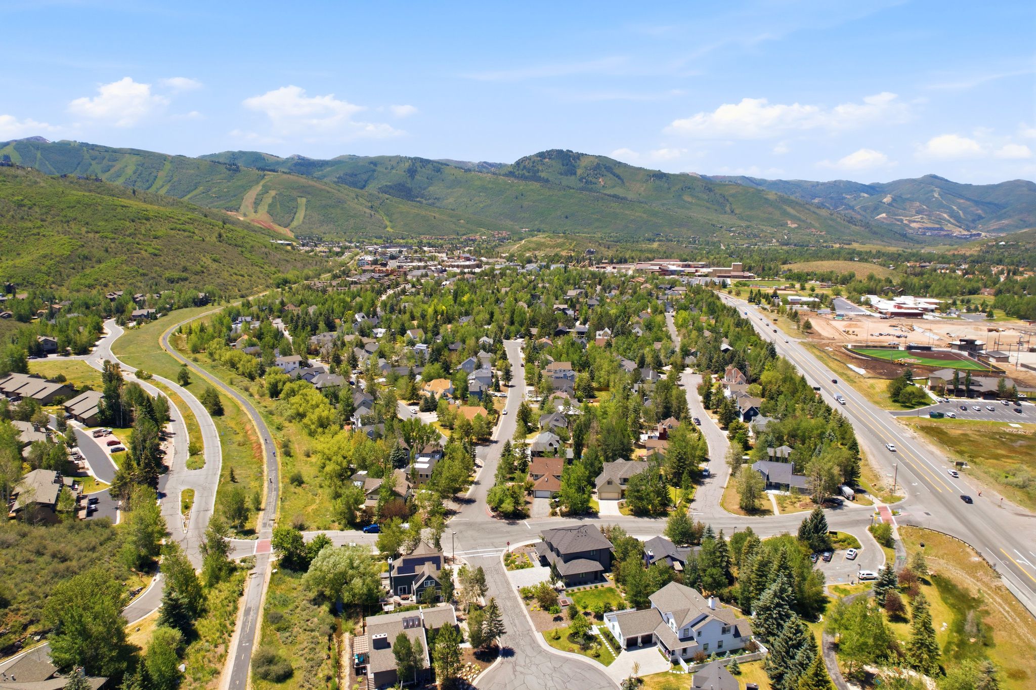 Residential area with established landscaping, surrounded by green mountains and a clear sky