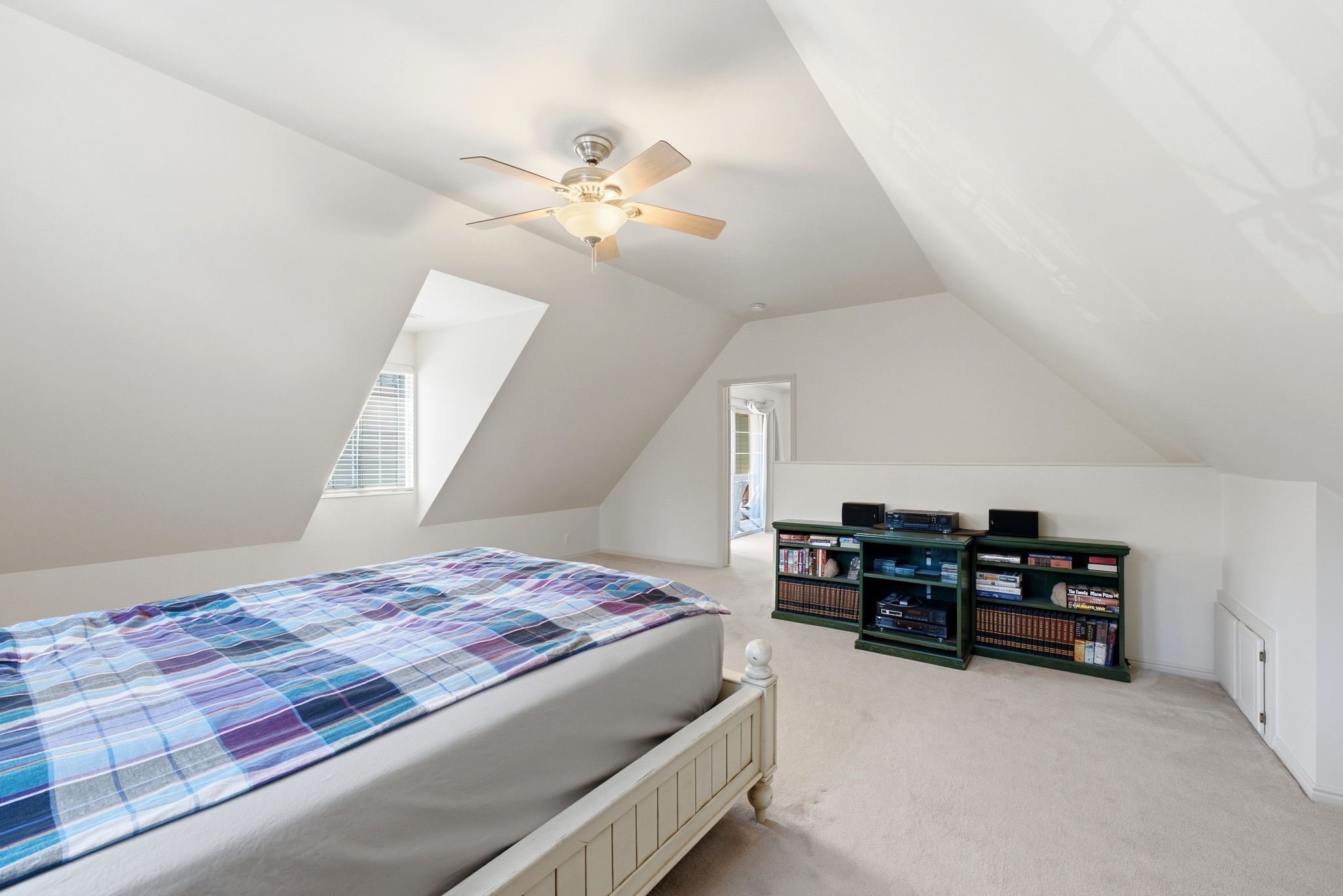 Carpeted room with sloped ceilings and a window featuring horizontal blinds
