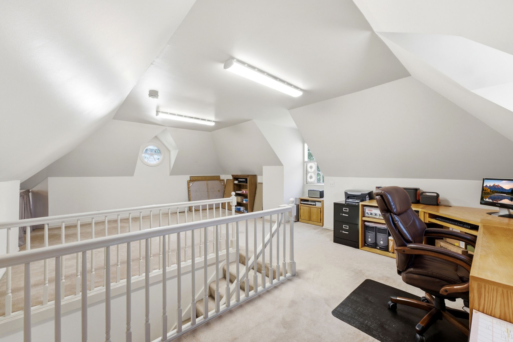 Open loft space featuring sloped ceilings, white painted walls, and neutral carpeting