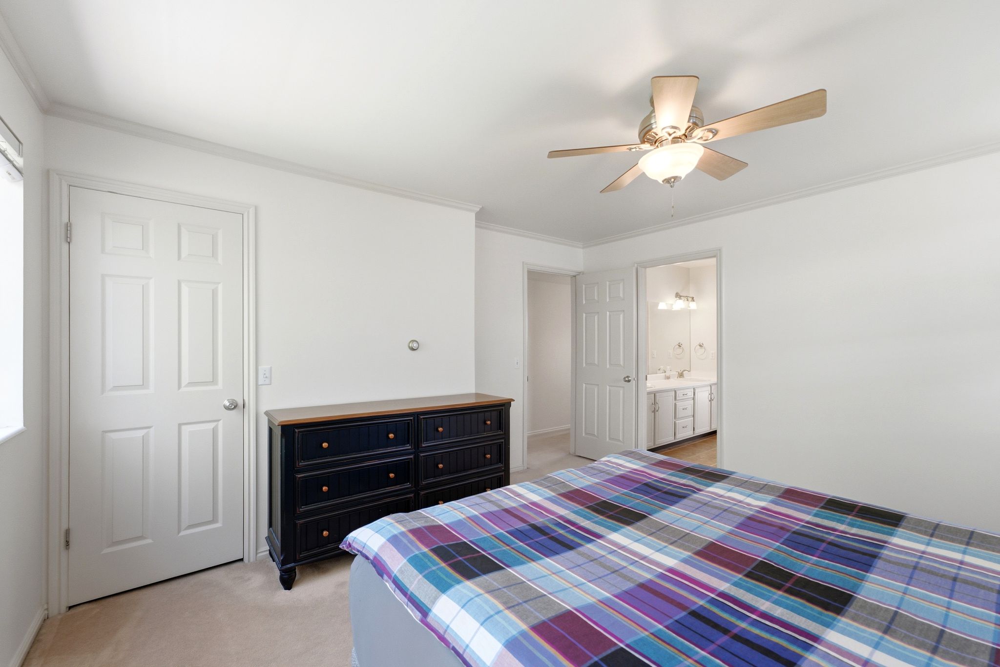 Bedroom featuring neutral carpeting, crown molding, a ceiling fan with integrated lighting, and an entryway to a bathroom with dual vanities