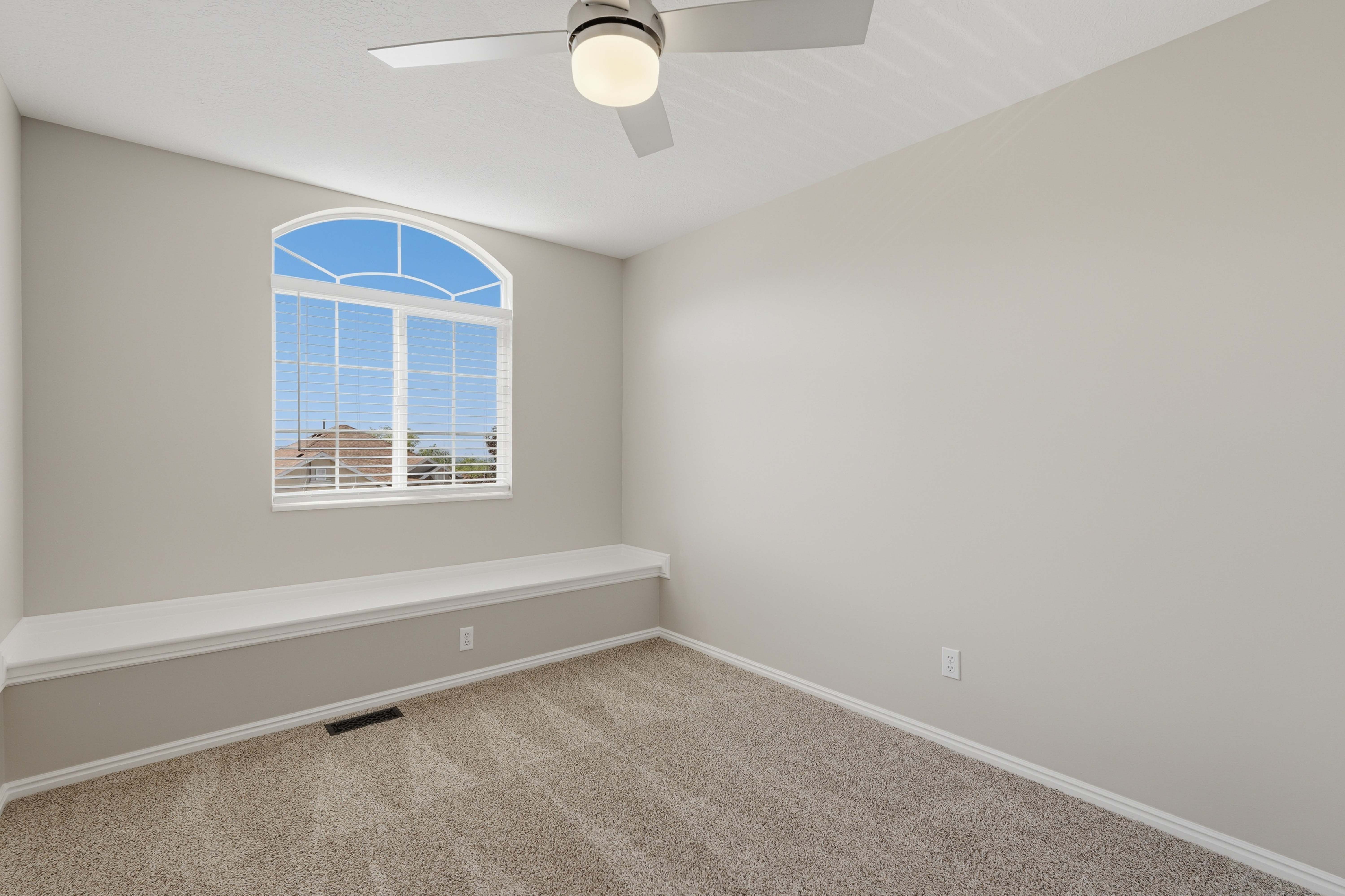 Arched window with grilles and white blinds set above a built-in window seat