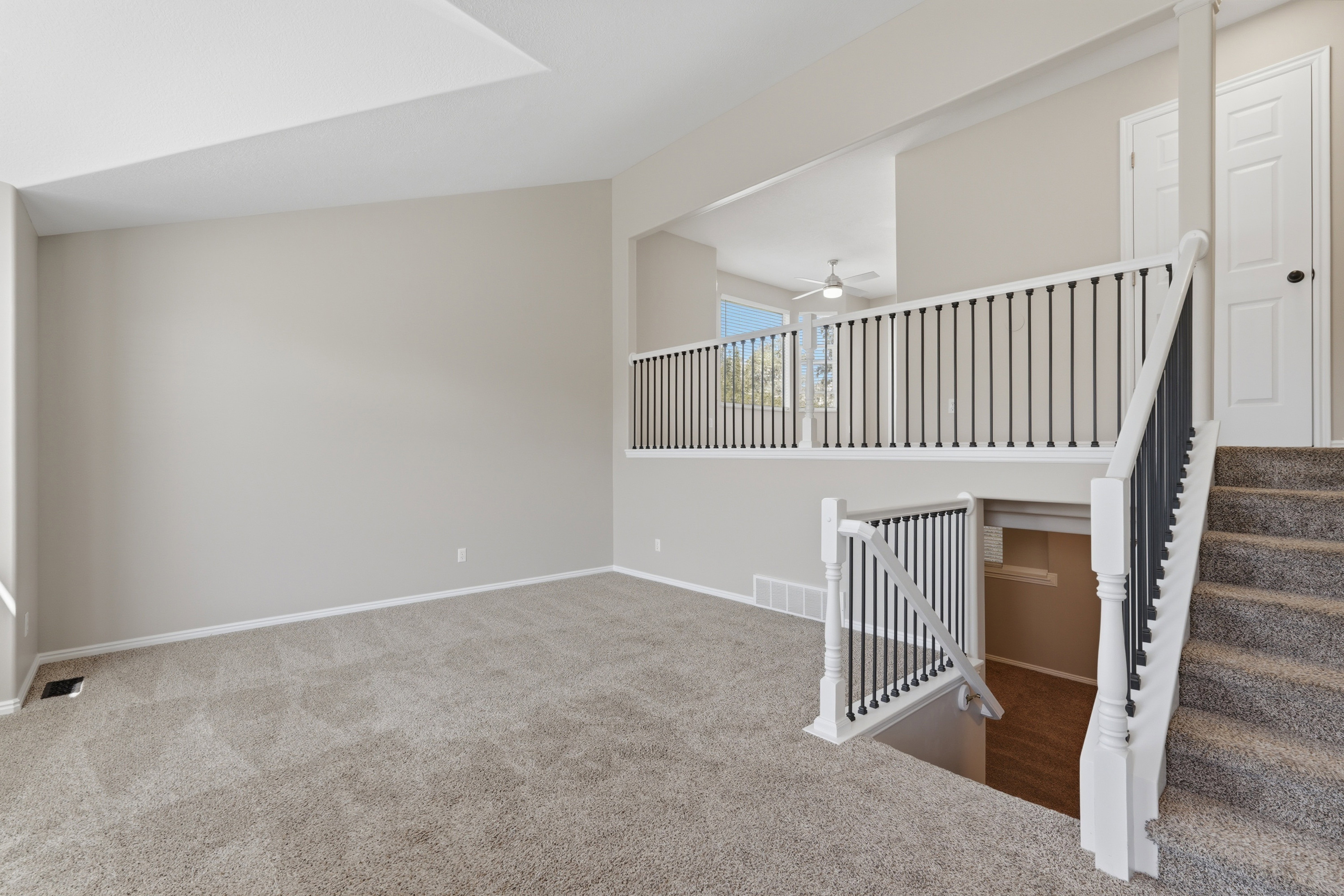 Carpeted living space with neutral wall tones and a vaulted ceiling