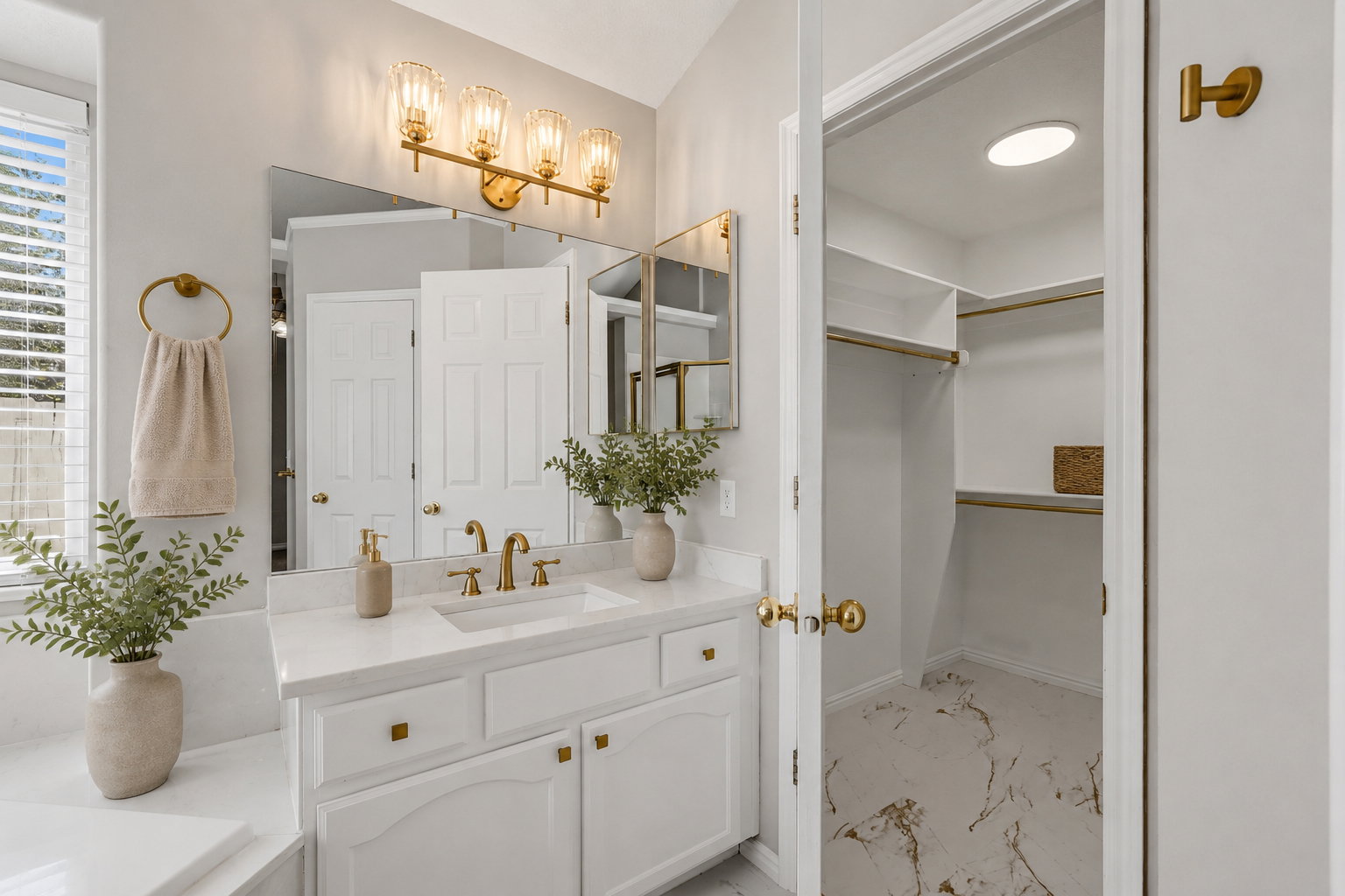 Bathroom vanity featuring a double sink with gold-finish fixtures, a large mirror, and an elegant four-light fixture. Staged virtually.