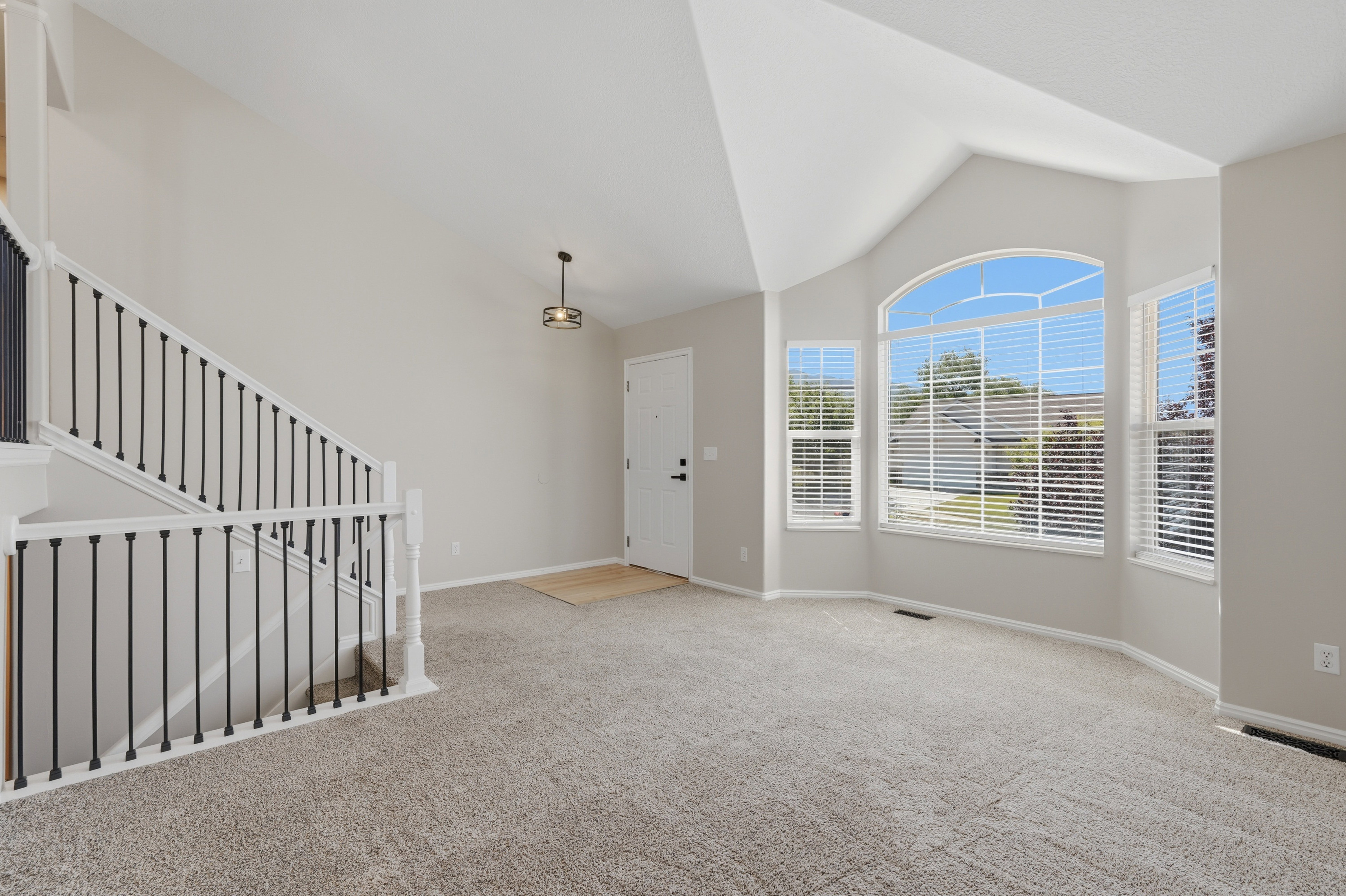 Carpeted entry area featuring a grand staircase with white banisters and black spindles