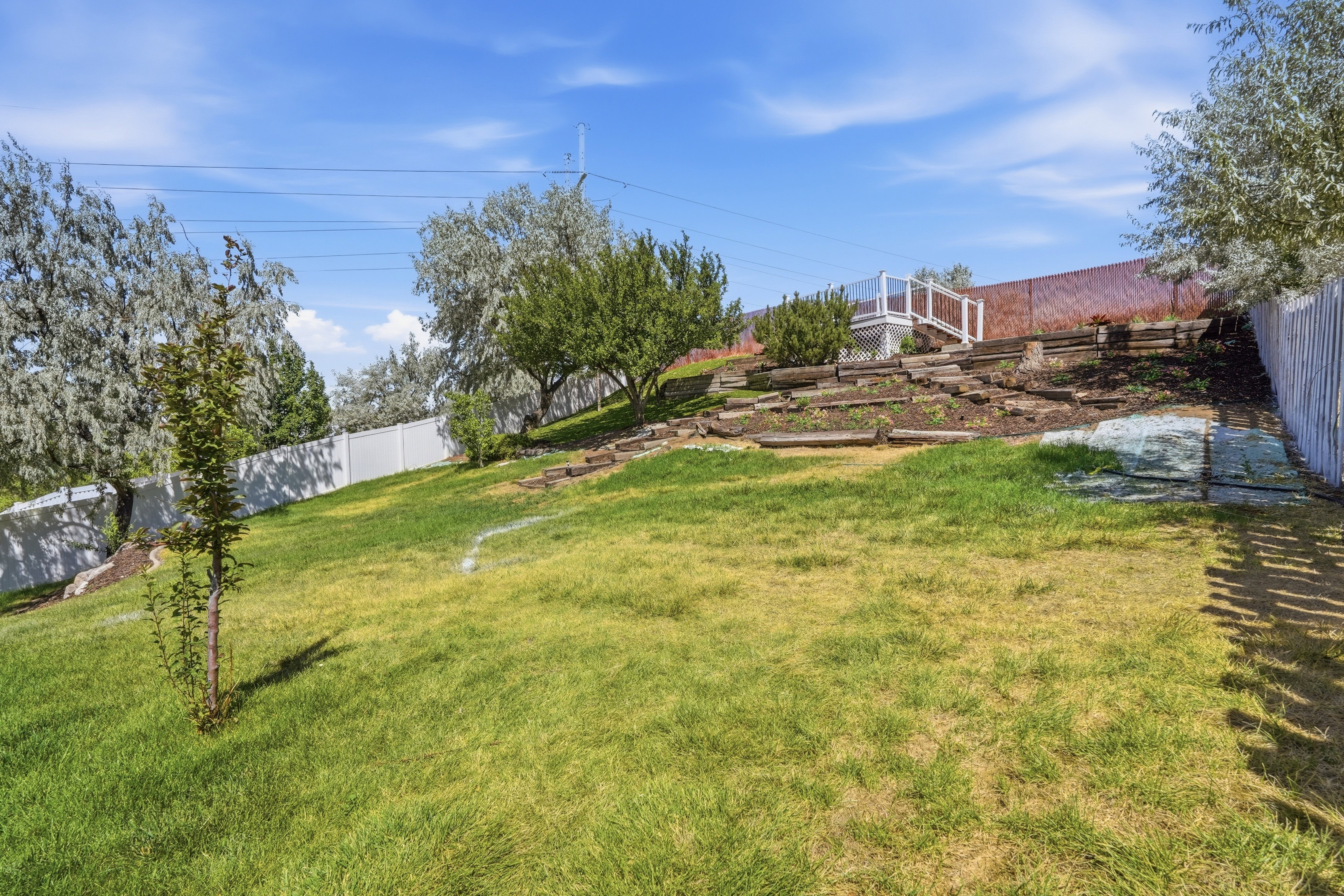 Expansive grassy yard with mature trees and a tiered garden area with a 360-degree viewing deck.