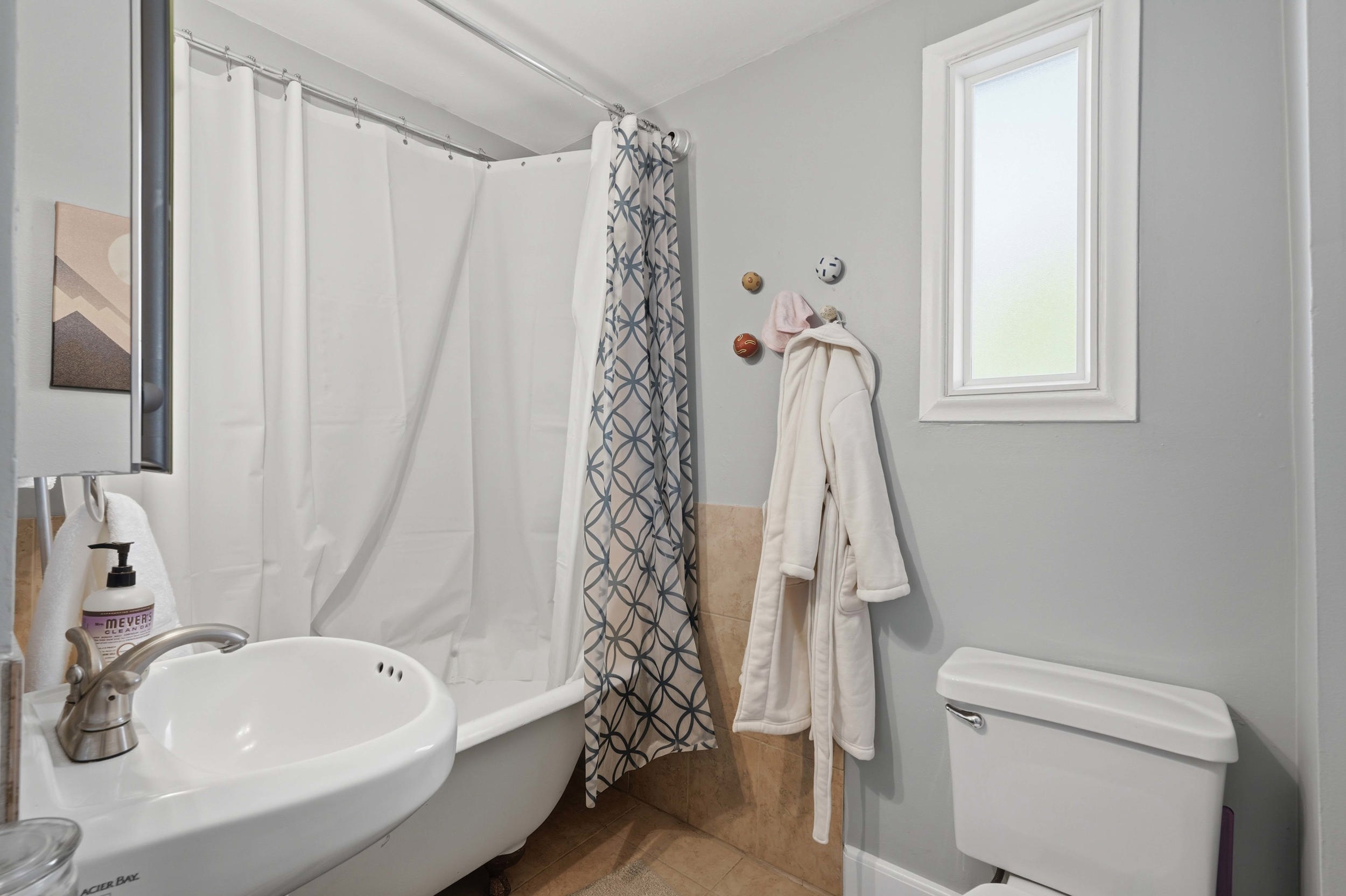 Bathroom featuring a pedestal sink, white toilet, and a window with white trim