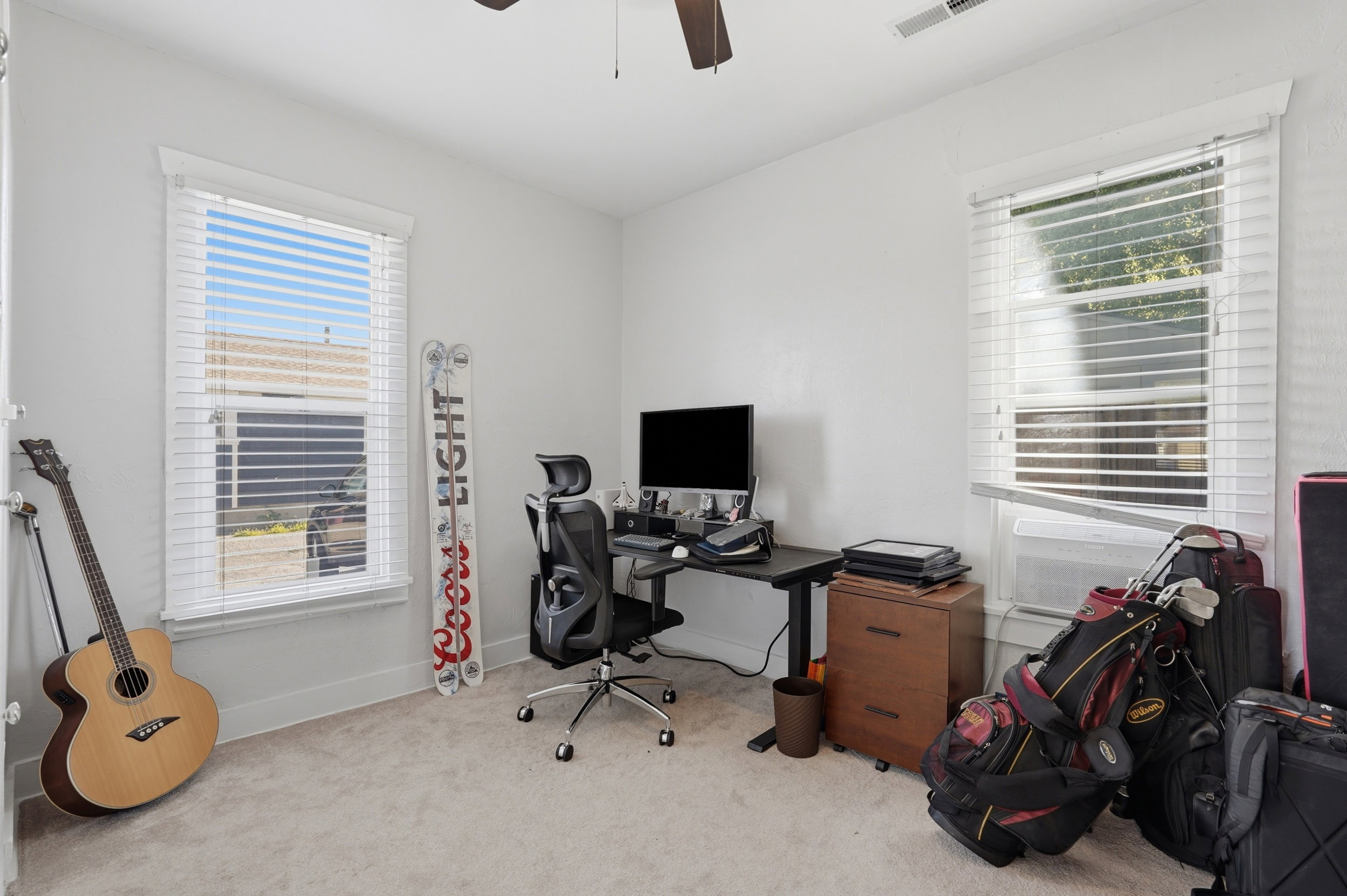 Carpeted room with a ceiling fan, two windows featuring white blinds, and white baseboards