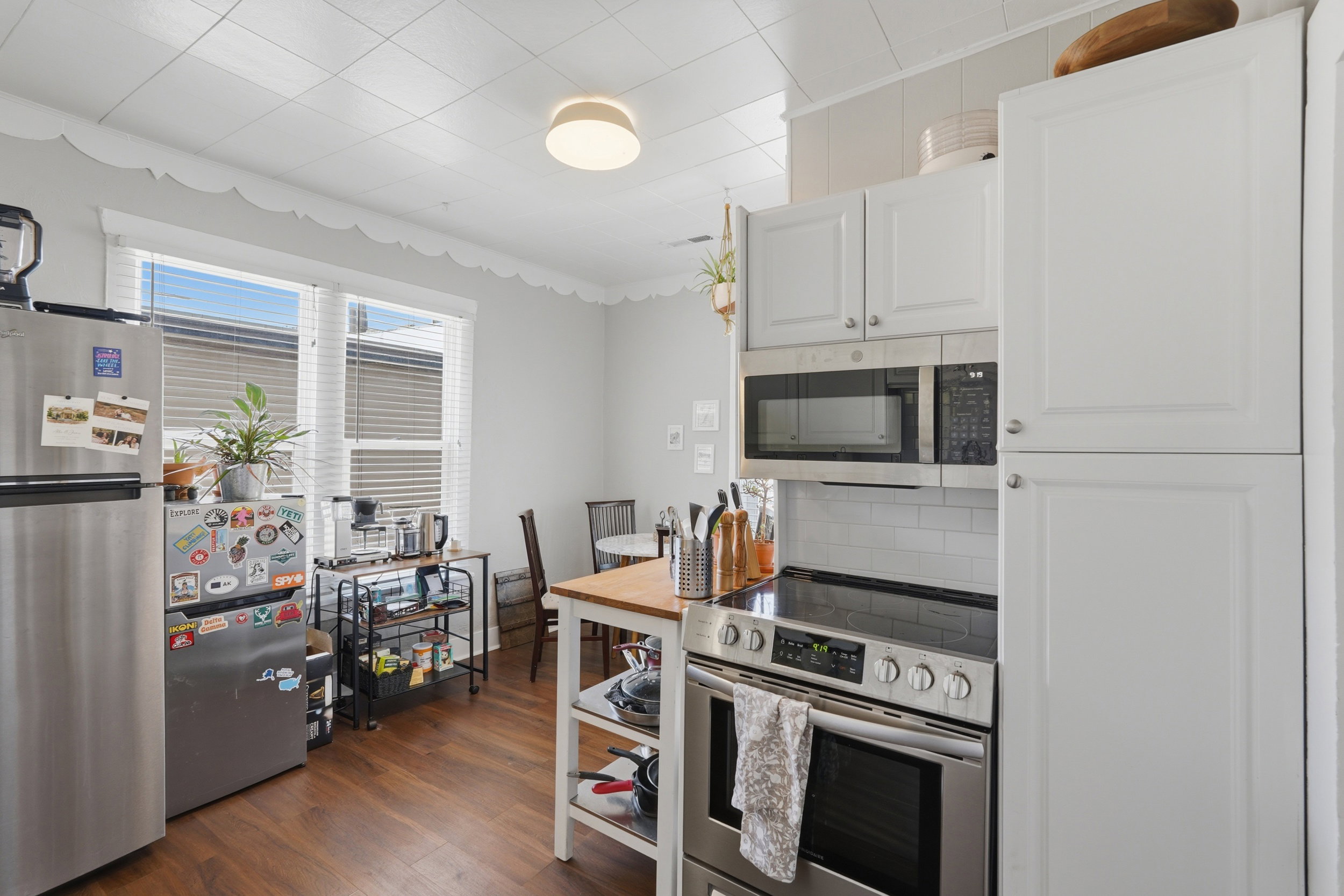 Kitchen featuring wood-finish flooring, white cabinetry, and stainless steel appliances
