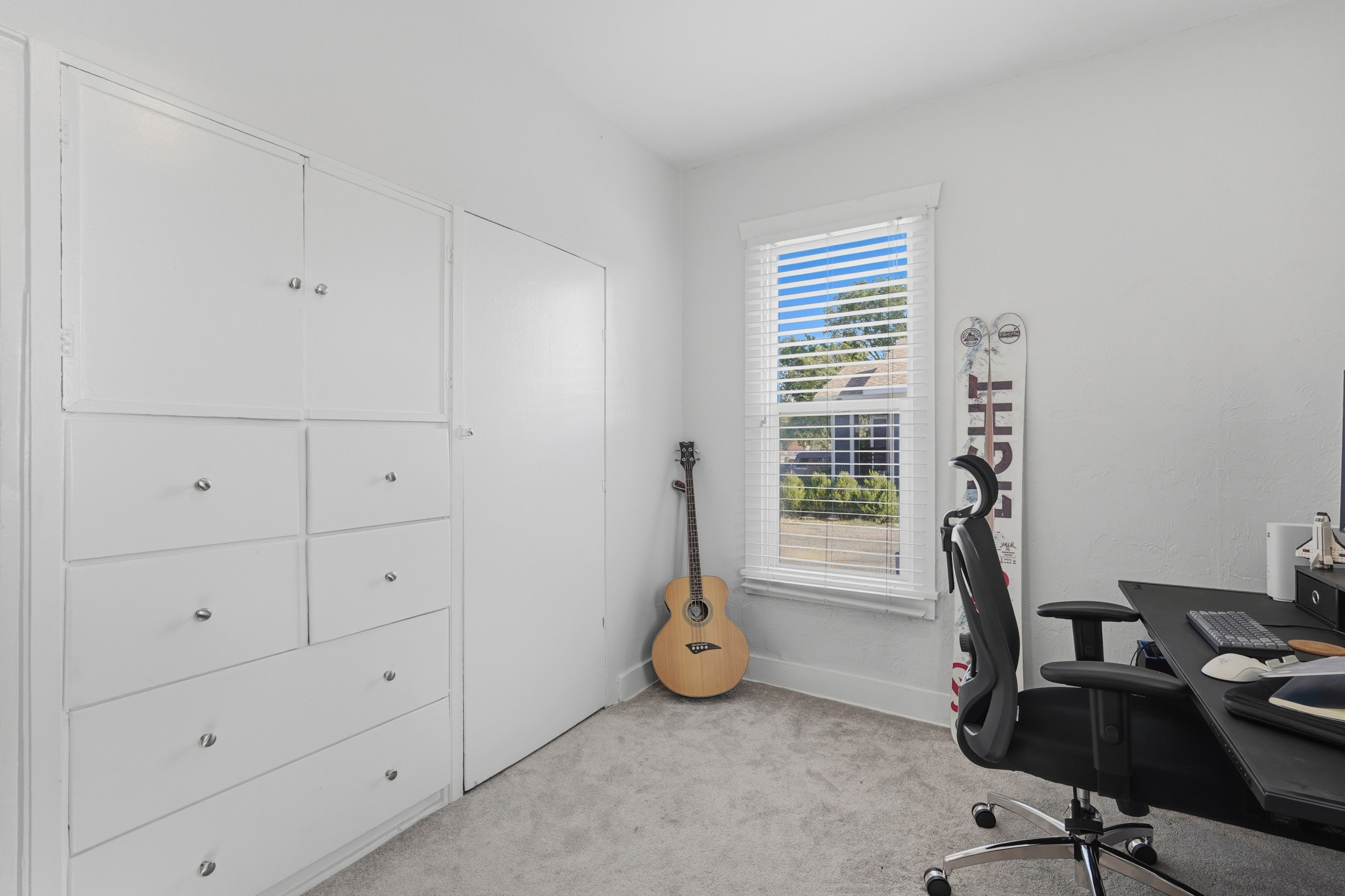 Room with light gray carpet flooring and white walls, featuring built-in cabinetry with multiple drawers and cabinet doors
