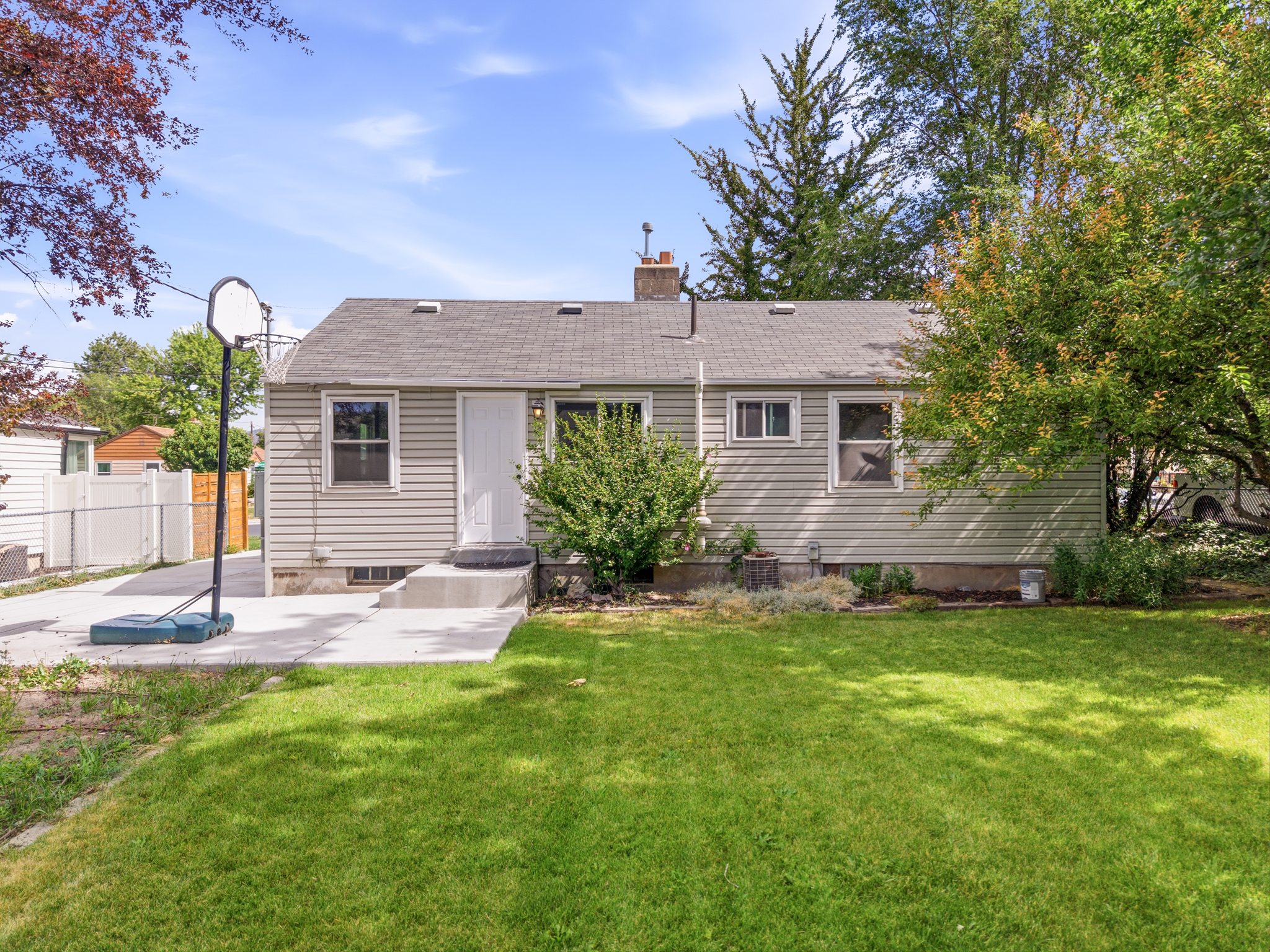 Rear exterior featuring light-toned horizontal siding, a gray shingle roof, and a concrete patio