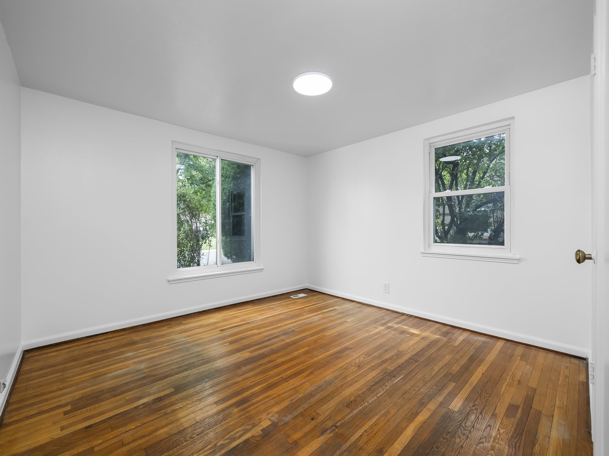 Bright room with wood-finish flooring, white walls, and a circular flush-mount ceiling light