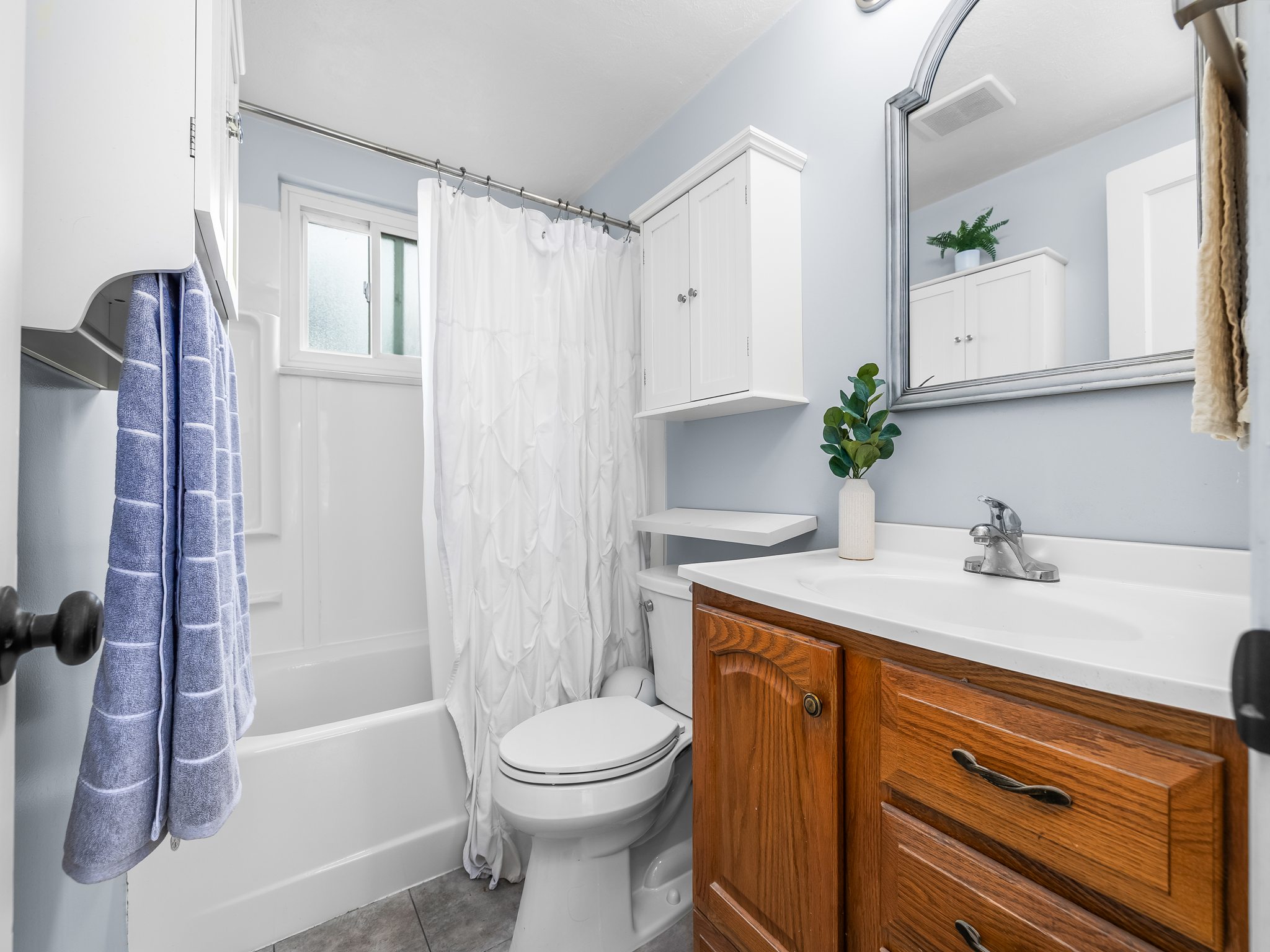 Bathroom featuring a wood-finish vanity with a white countertop, an integrated sink, and a framed mirror